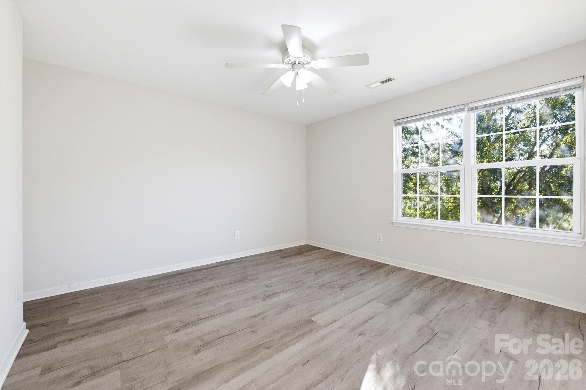 Spacious bedroom with a ceiling fan, large windows, and modern flooring. - 5718 Natick Drive, Charlotte