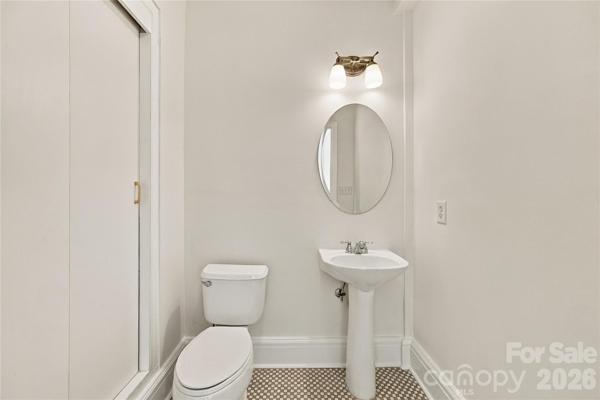 Charming half bath with original checkerboard tile in warm earth tones and convenient closet storage. - 712 Louise Avenue, Charlotte