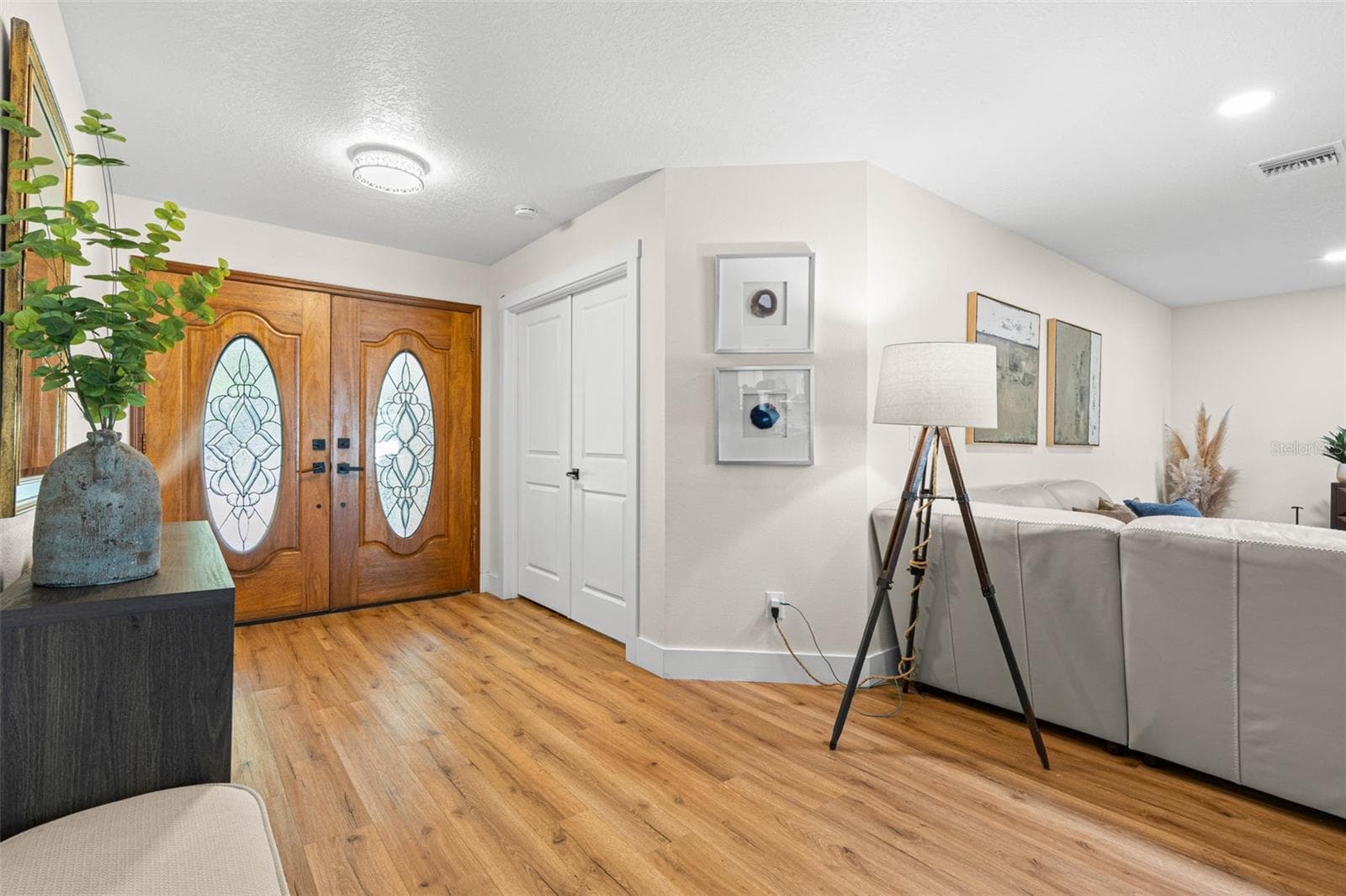 Step inside to a bright, welcoming entryway featuring decorative double doors with leaded-glass inserts, beautiful wood-look luxury vinyl flooring, recessed lighting, and a convenient entry closet. The open layout offers an inviting glimpse into the spacious living area. - 3013 GRAHAM LN, TAMPA