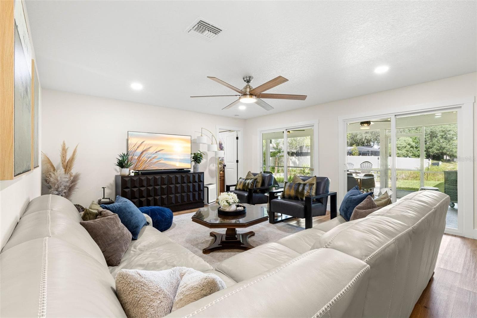 The spacious living room offers plenty of room for comfortable seating and entertaining, with recessed lighting, a contemporary ceiling fan, luxury vinyl flooring, and two sets of sliding glass doors that fill the space with natural light and provide access to the screened porch. - 3013 GRAHAM LN, TAMPA