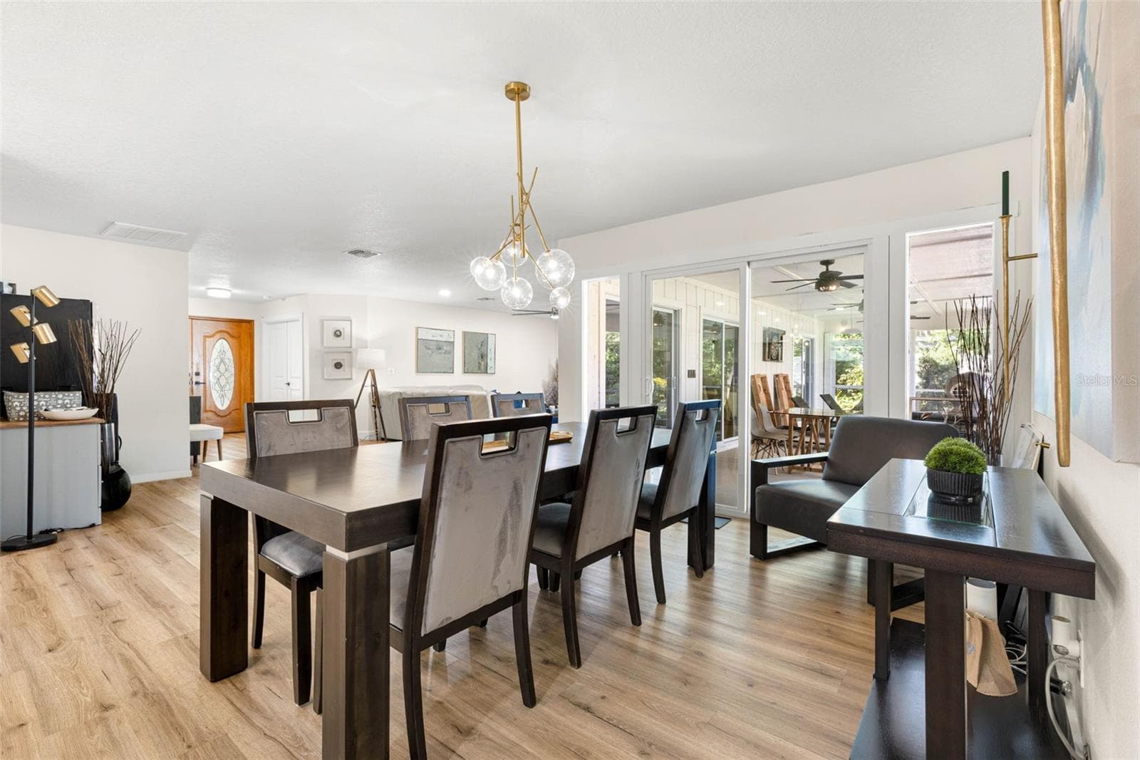 The beautifully appointed dining area features a striking contemporary gold chandelier with glass globe shades, creating an elegant focal point. Generous proportions accommodate a large dining table, while sliding glass doors provide natural light and access to the screened outdoor living area. - 3013 GRAHAM LN, TAMPA
