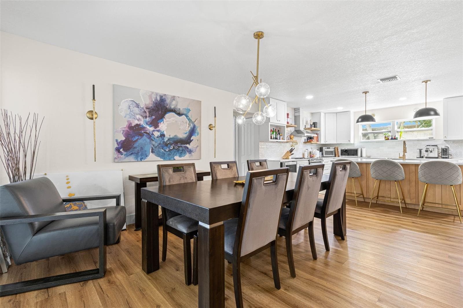 The dining area flows effortlessly into the beautifully updated kitchen, creating an ideal setting for everyday meals and entertaining. A contemporary glass-globe chandelier complements the kitchen's gold fixtures, pendant lighting, and inviting breakfast bar with seating for four. - 3013 GRAHAM LN, TAMPA