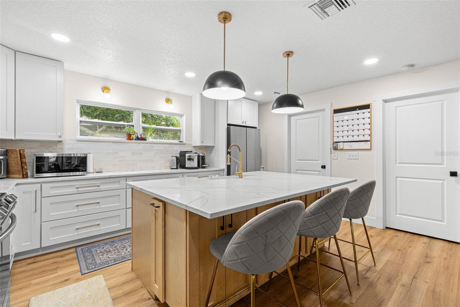 The oversized center island provides an expansive quartz countertop for meal preparation, casual dining, and entertaining. A gold gooseneck faucet, contemporary pendant lighting, abundant cabinetry, and a wide window above the counter add both style and functionality. - 3013 GRAHAM LN, TAMPA