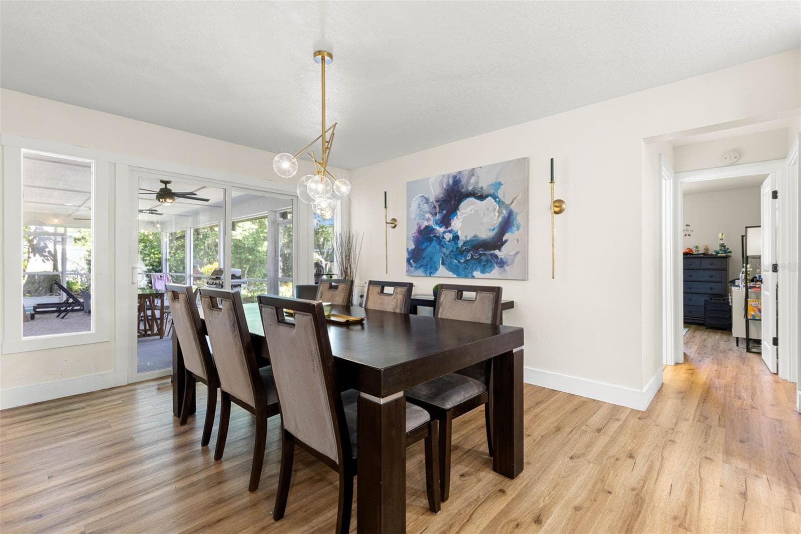 The inviting dining area comfortably accommodates a large table for gatherings and special occasions. Sliding glass doors open to the screened porch, extending the entertaining space outdoors, while an elegant gold chandelier and coordinating wall sconces add a sophisticated touch. - 3013 GRAHAM LN, TAMPA