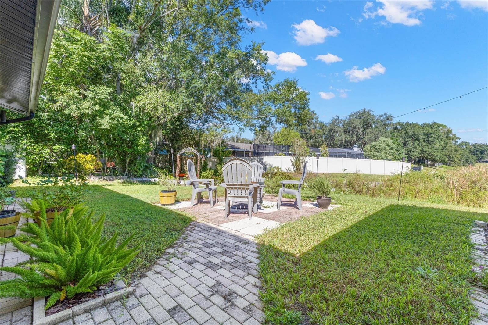 A charming paver walkway leads to an inviting outdoor seating area, perfect for morning coffee, evening conversations, or gathering around a fire pit. Mature trees, lush landscaping, and an open lawn create a peaceful backyard retreat just steps from the pond. - 3013 GRAHAM LN, TAMPA