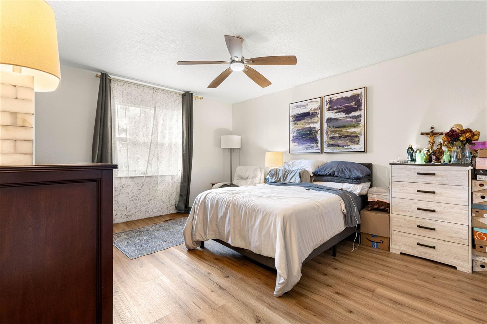 Bedroom three offers a generously proportioned layout with warm wood-look luxury vinyl flooring, a contemporary ceiling fan, neutral walls, and a large window that welcomes natural light. Plenty of room for a full bedroom furniture arrangement without feeling crowded. - 3013 GRAHAM LN, TAMPA