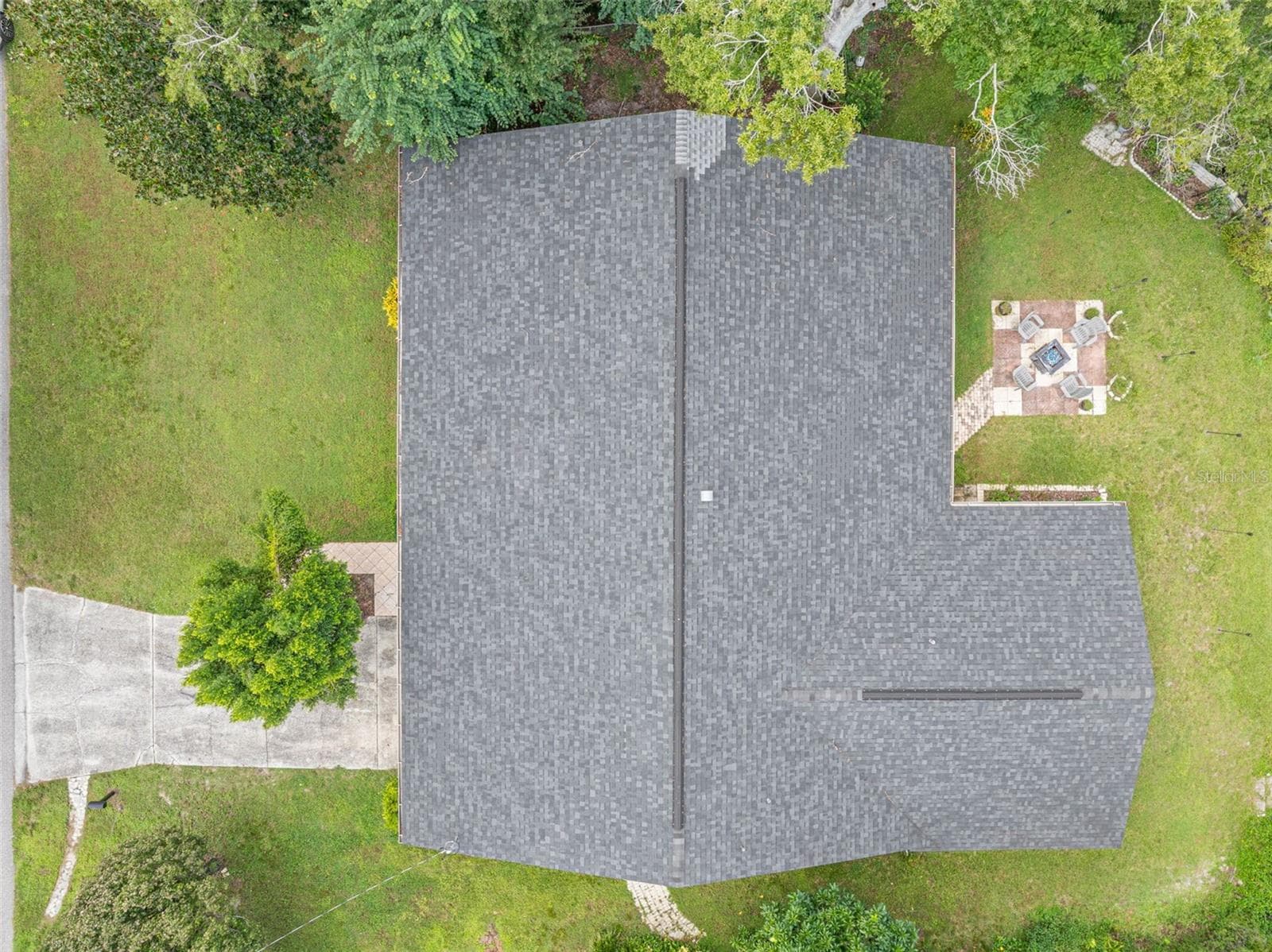 A bird-eye perspective highlights the home's expansive single-story footprint, dimensional shingle roof replaced in 2021, and surrounding lawn areas. The paver patio and fire pit area add character to the outdoor setting on this .34-acre property. - 3013 GRAHAM LN, TAMPA