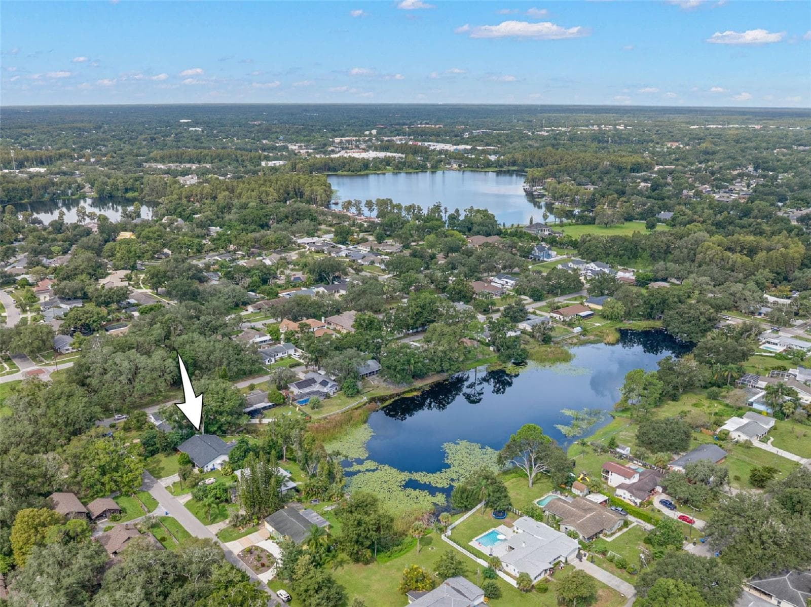 An aerial view highlights the home's setting along a picturesque pond, surrounded by mature trees and established residences in the heart of Carrollwood. Enjoy the tranquility of waterfront living while remaining close to the shopping, dining, recreation, and conveniences of Tampa. - 3013 GRAHAM LN, TAMPA