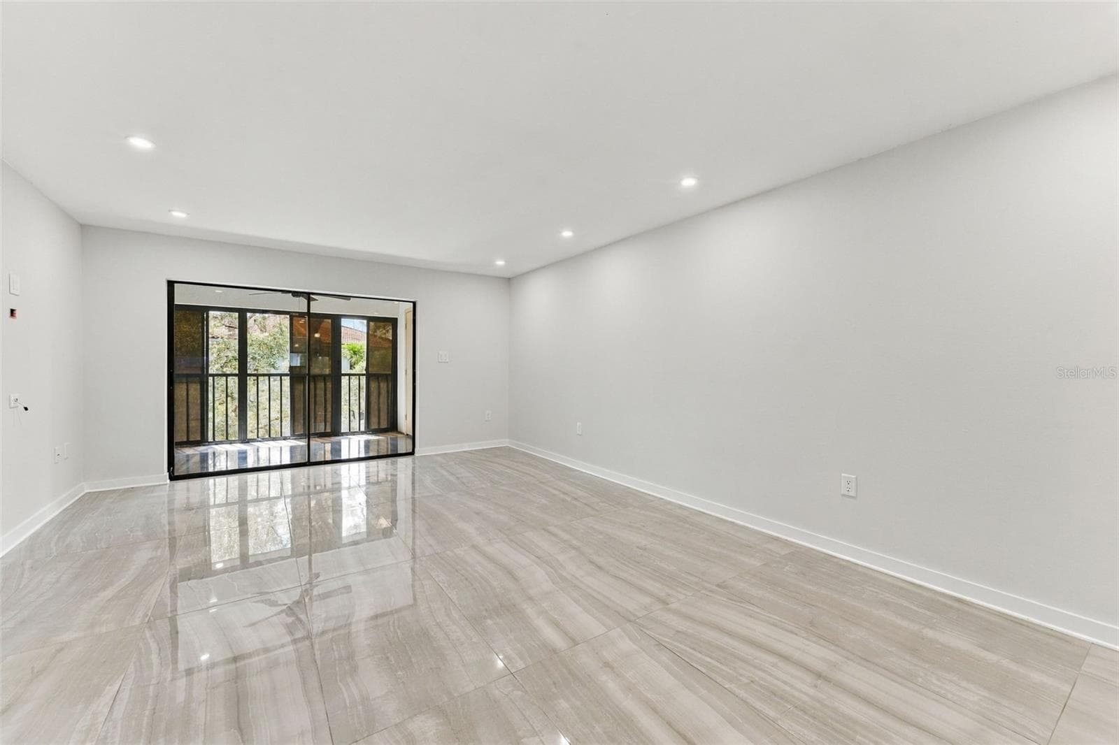 Living room with new tile flooring and sliding glass doors leading to the back patio - 2650 COUNTRYSIDE BLVD #A306, CLEARWATER