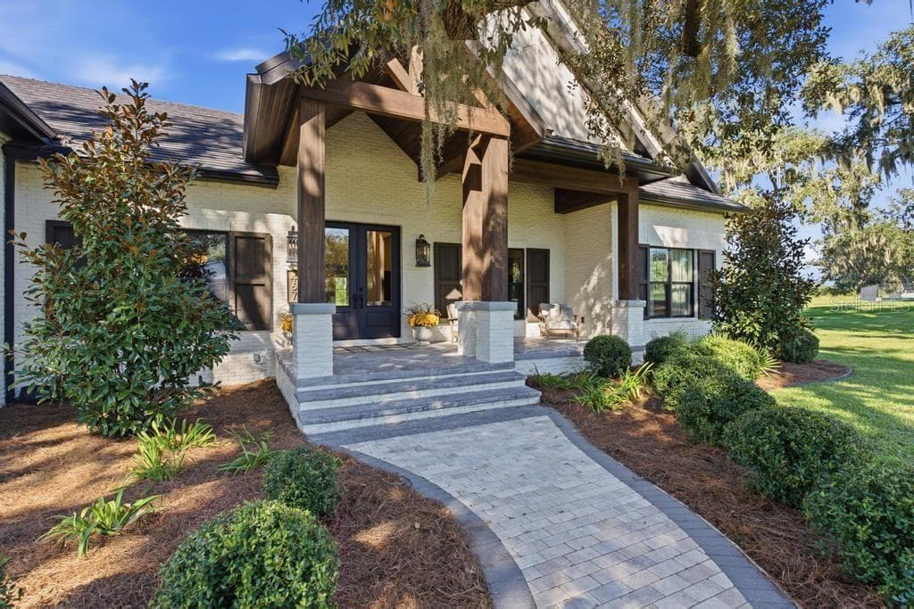 Brick walkway leading to front porch with large sitting area with easy to clean epoxy floors! - 467 LONG AND WINDING RD, HOWEY IN THE HILLS