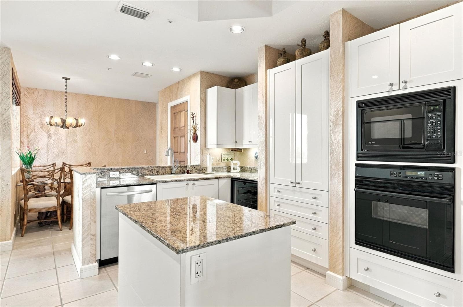 Thoughtfully designed kitchen with shaker style cabinetry, center island with cabinets and pull out drawers, planning desk, and wine refrigerator and closet pantry. - 2185 GULF OF MEXICO DR #243, LONGBOAT KEY