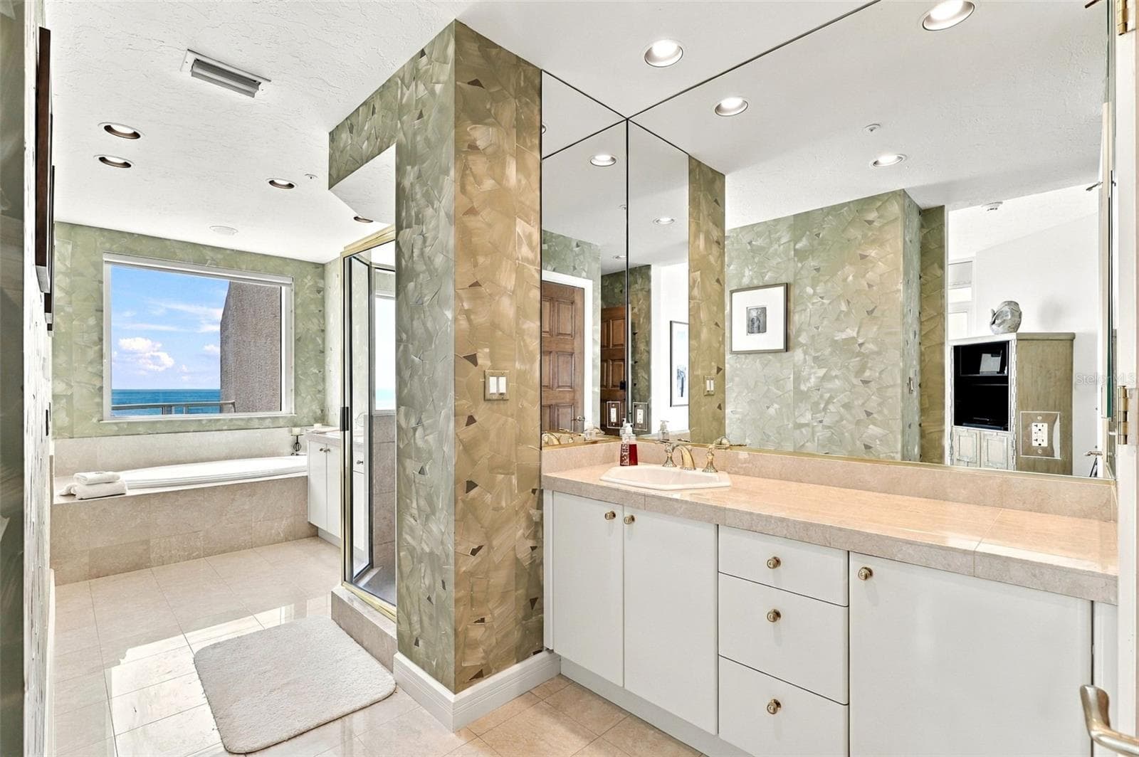 The primary ensuite bathroom offers dual vanities, marble floors and a huge spa tub overlooking the water and beach view. - 2185 GULF OF MEXICO DR #243, LONGBOAT KEY