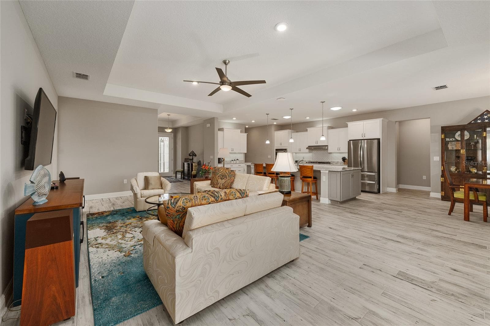 Designed for comfortable living and effortless entertaining, this spacious open floor plan showcases neutral finishes, ceramic plank flooring, elegant tray ceilings, upgraded hardware, dovetail drawers, and ceiling fans with integrated lighting, creating a warm and inviting atmosphere throughout. - 8290 SW 92ND CIR, OCALA