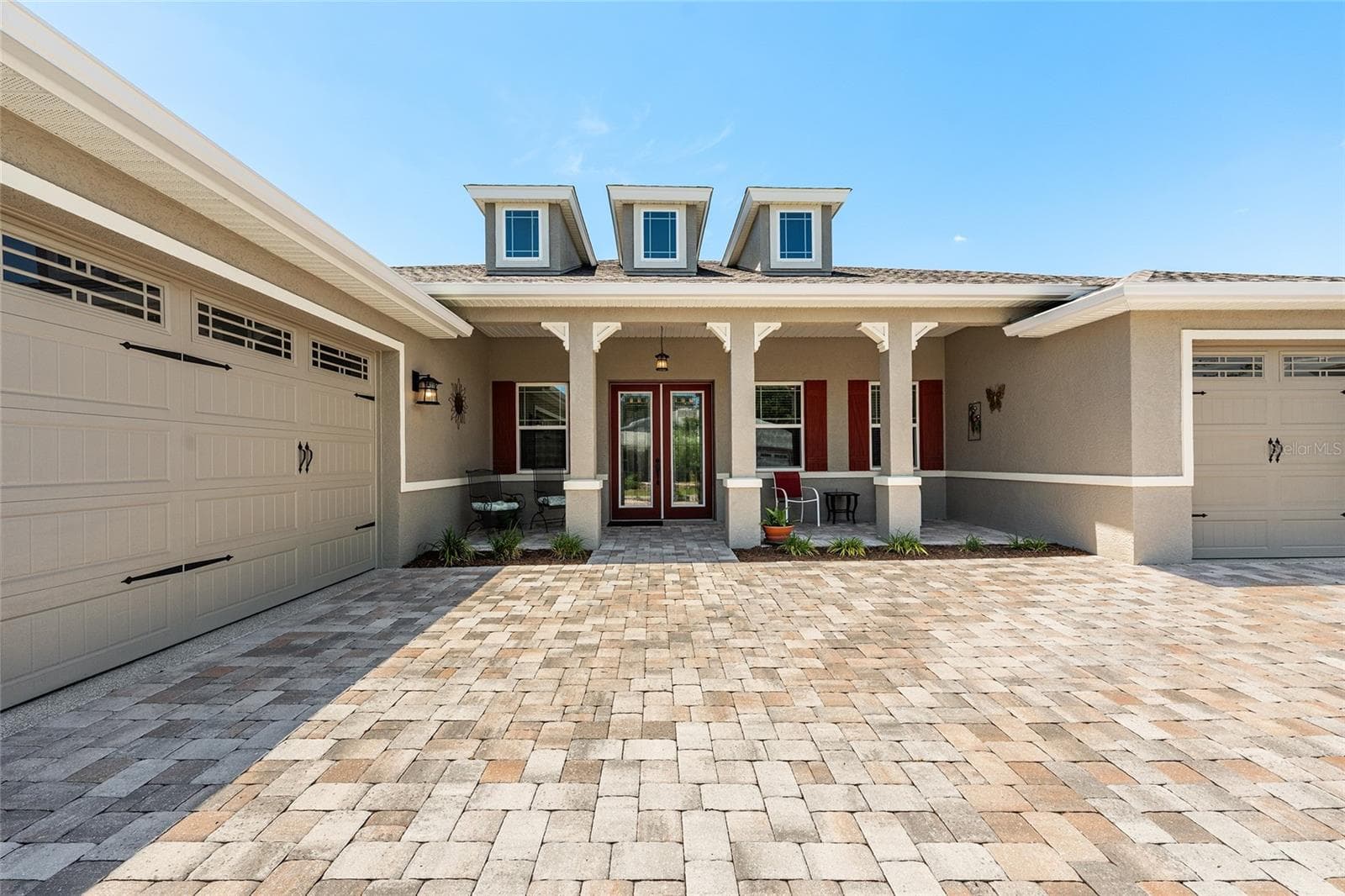 Beautiful 2021 Aberdeen model offering exceptional curb appeal with an expansive covered front porch, elegant leaded-glass double entry doors, attractive paver driveway, and professionally landscaped grounds that create a warm and welcoming first impression. - 8290 SW 92ND CIR, OCALA