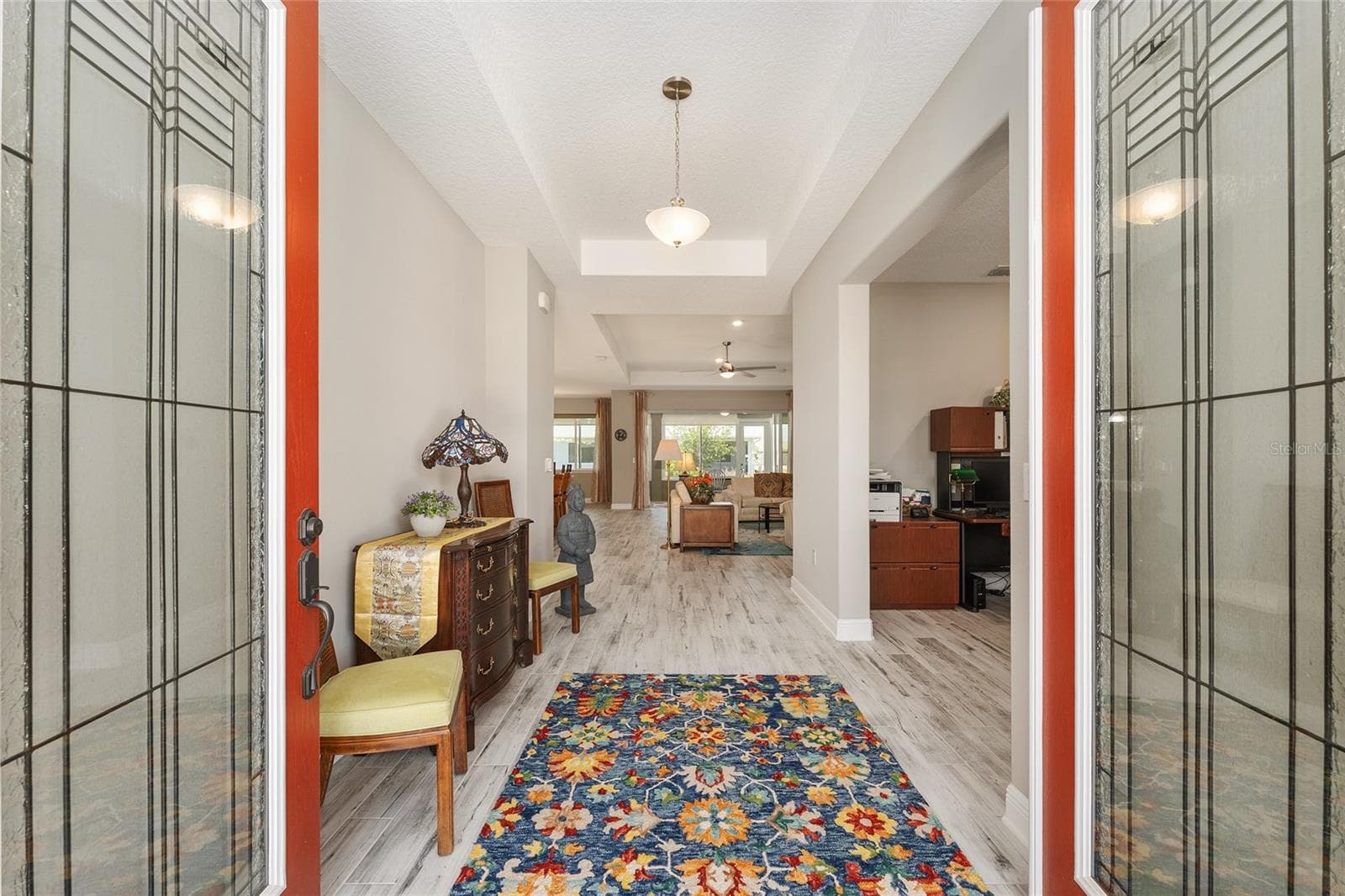 Inviting foyer featuring elegant leaded-glass double entry doors, a decorative tray ceiling, and ceramic plank flooring, creating a bright and welcoming introduction to the home. - 8290 SW 92ND CIR, OCALA
