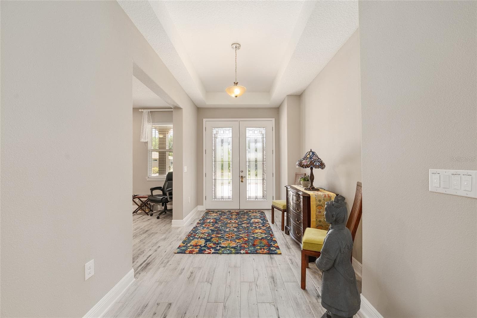 Spacious foyer with an elegant tray ceiling and a welcoming layout, offering a glimpse into the versatile flex room—perfect for a home office, sitting room, or quiet retreat. - 8290 SW 92ND CIR, OCALA