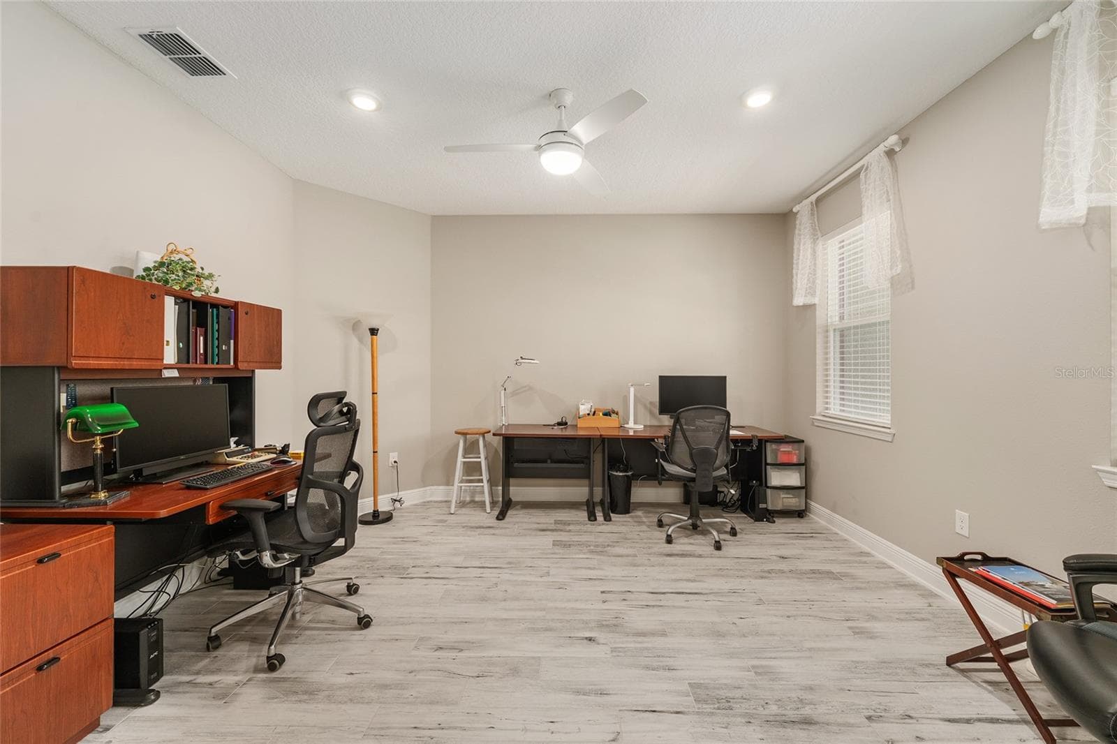 Generously sized flex room featuring ceramic plank flooring, neutral finishes, recessed lighting, and a ceiling fan with integrated lighting. Large windows bring in natural light, creating an inviting space for a home office, sitting room, or hobby room. - 8290 SW 92ND CIR, OCALA