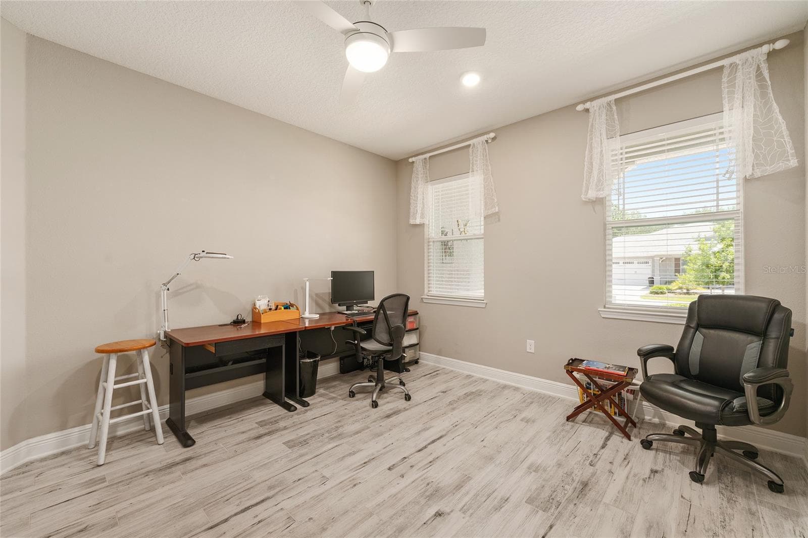 Two front-facing windows fill this spacious flex room with natural light, offering a bright and comfortable setting for a home office, reading lounge, or creative workspace. - 8290 SW 92ND CIR, OCALA