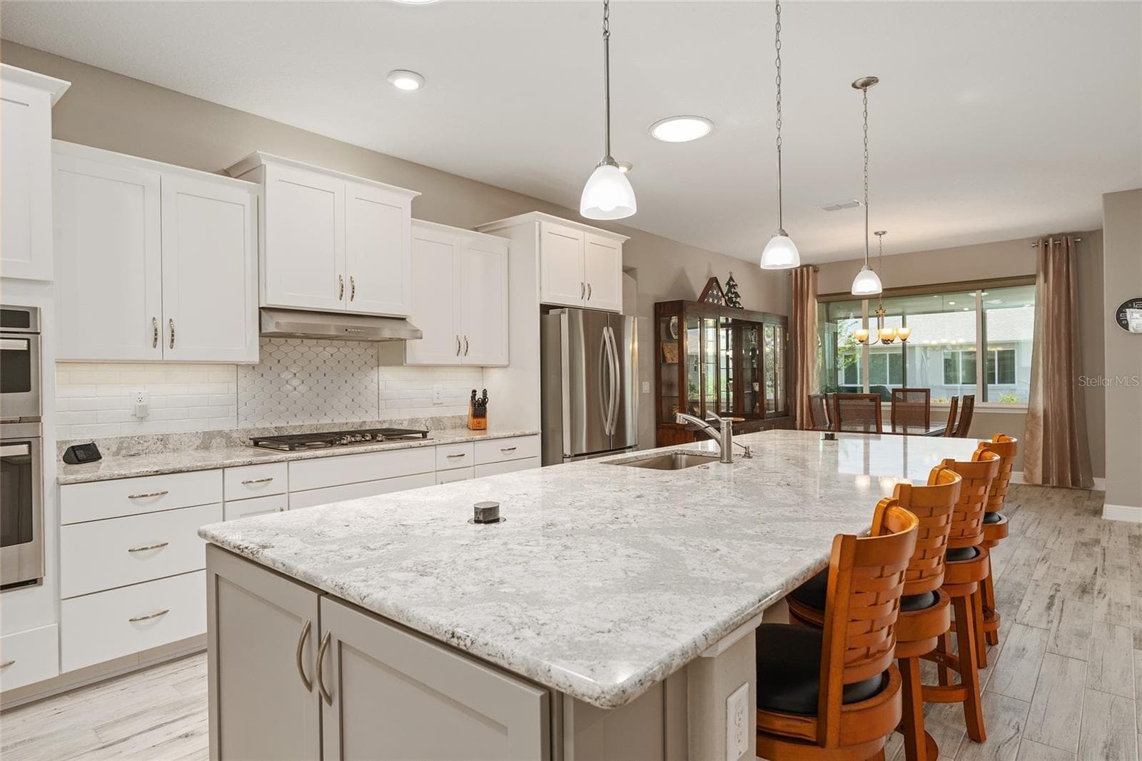 Expansive Cambria quartz kitchen island featuring two concealed pop-up outlets, a built-in soap dispenser, additional end cabinetry for storage, and generous seating—combining style and everyday convenience. - 8290 SW 92ND CIR, OCALA