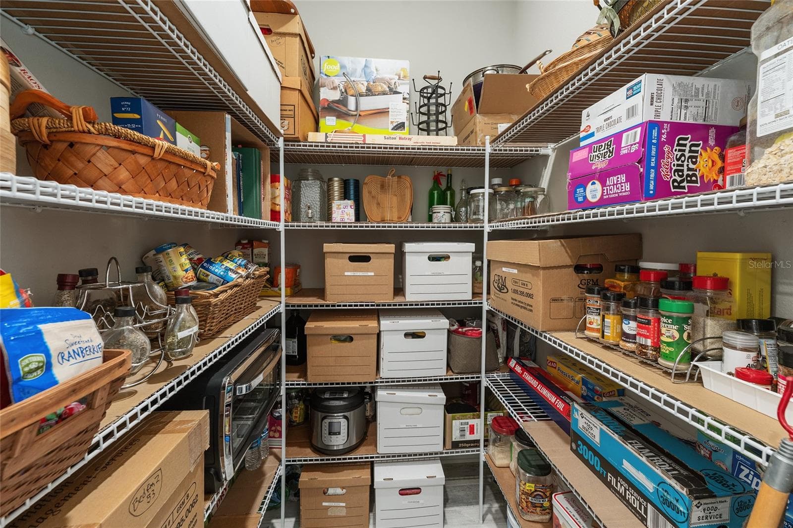 Spacious walk-in pantry conveniently located off the kitchen near the two-car garage for easy grocery unloading, featuring abundant shelving and generous storage space for food, small appliances, and household essentials. - 8290 SW 92ND CIR, OCALA