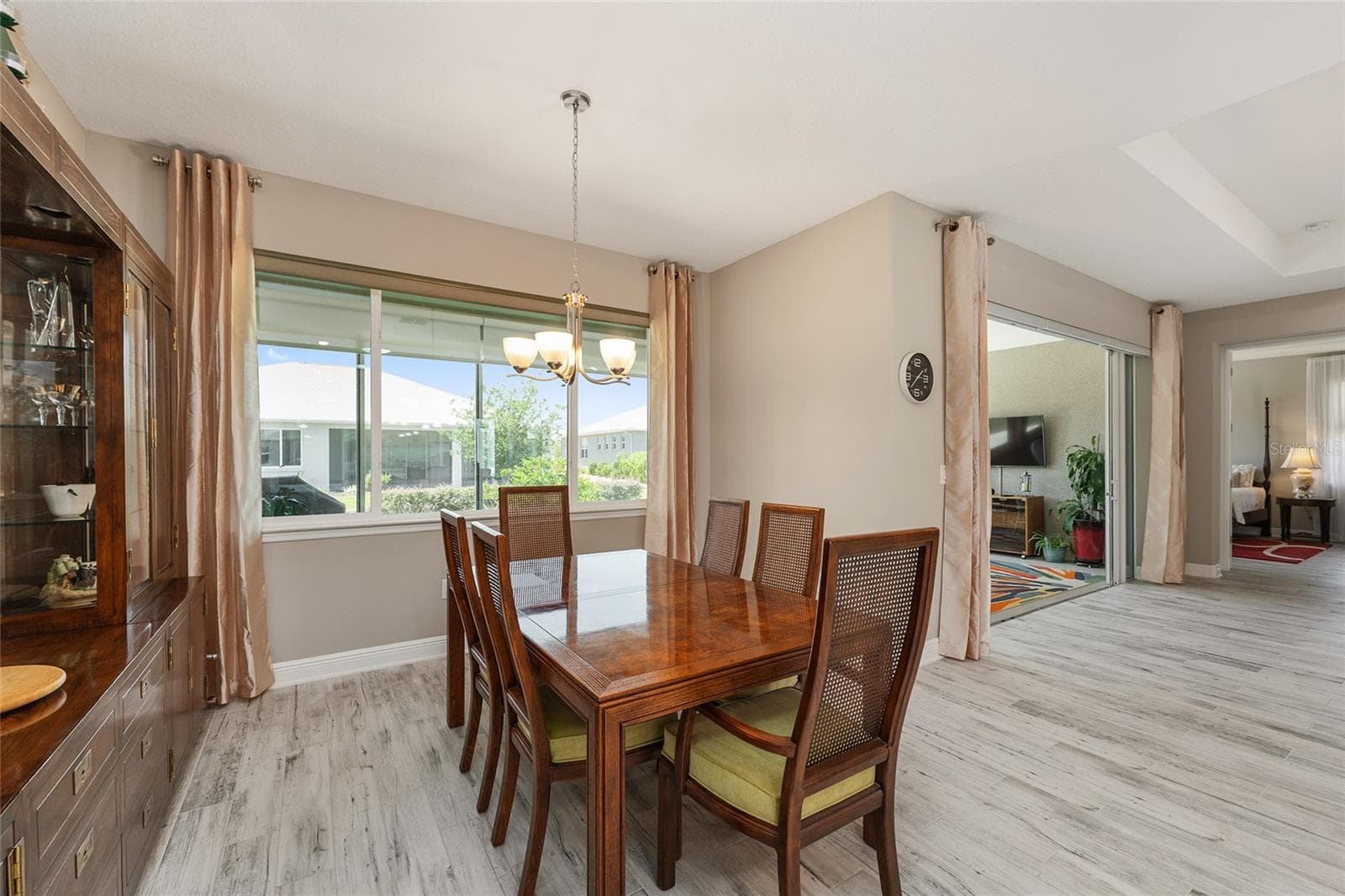 Bright and inviting dining area featuring large windows that fill the space with natural light, ceramic plank flooring, neutral finishes, and an open flow to the kitchen and great room, with convenient access to the enclosed lanai. - 8290 SW 92ND CIR, OCALA