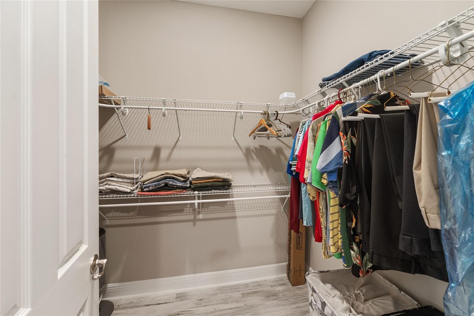 First of two walk-in closets in the primary suite, featuring wraparound shelving and generous hanging space for convenient storage and organization. - 8290 SW 92ND CIR, OCALA