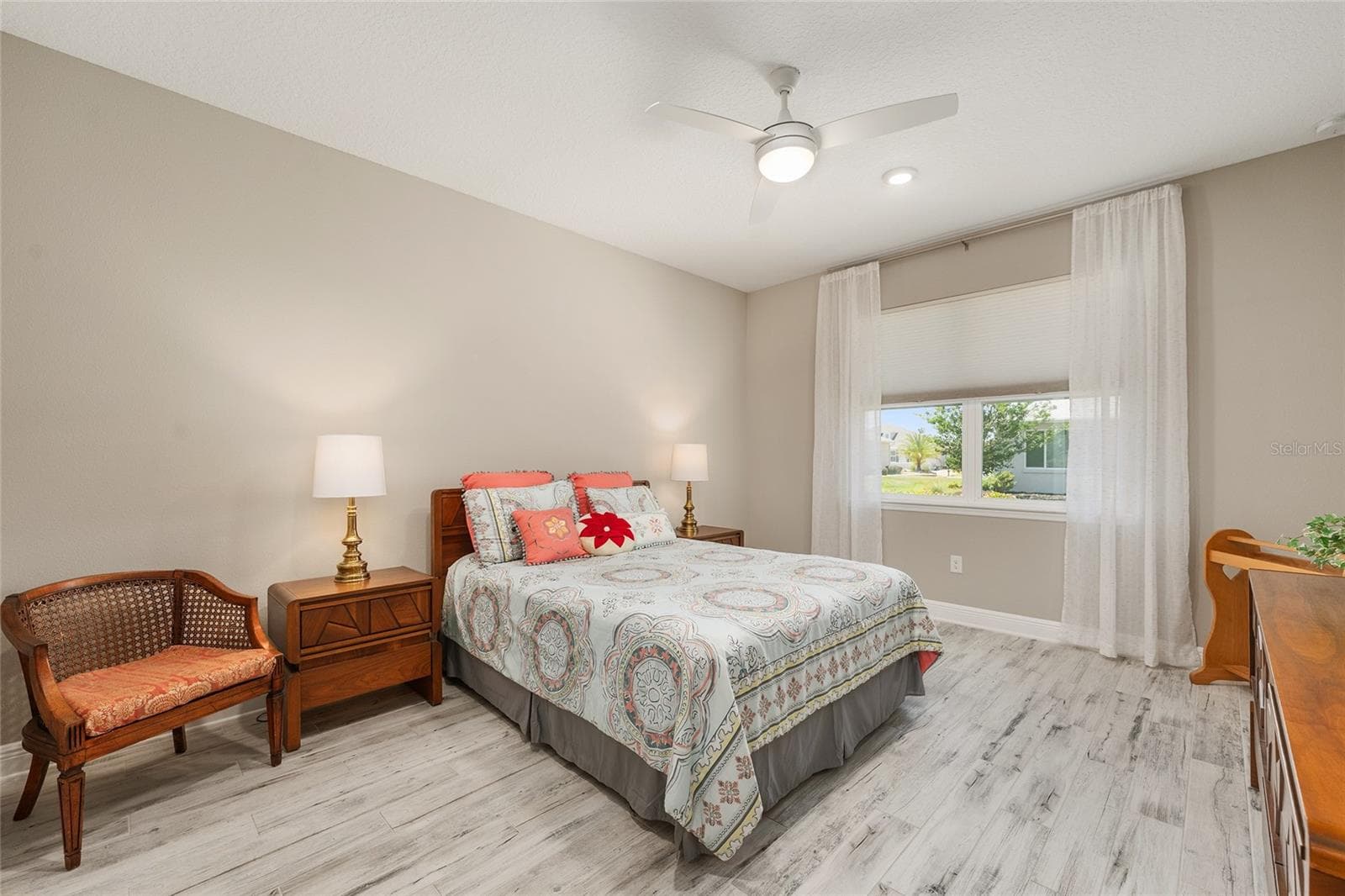 Spacious second primary suite featuring ceramic plank flooring, a ceiling fan with integrated lighting, and a large window that welcomes natural light. Complete with a private ensuite bathroom, this inviting retreat offers comfort and privacy for extended guests or multigenerational living. - 8290 SW 92ND CIR, OCALA