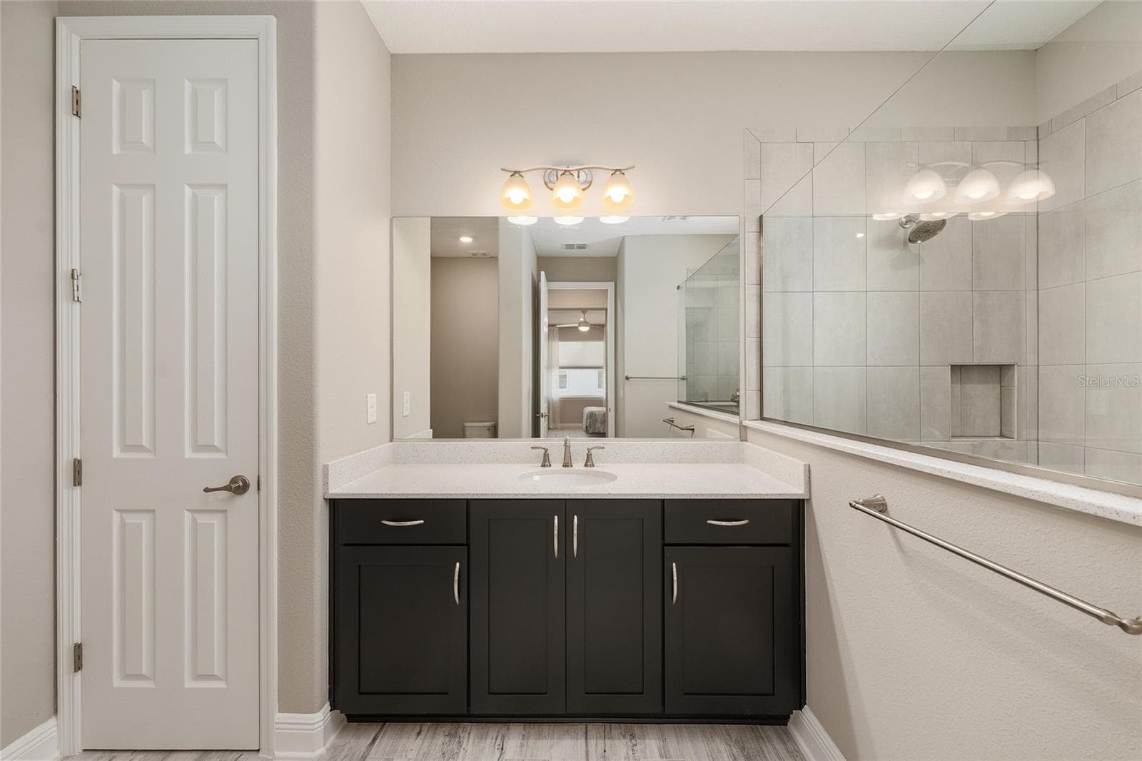 Second primary suite's private ensuite bathroom features a spacious vanity with a light-colored countertop, rich espresso cabinetry, generous storage, a large mirror, and a convenient linen closet. - 8290 SW 92ND CIR, OCALA