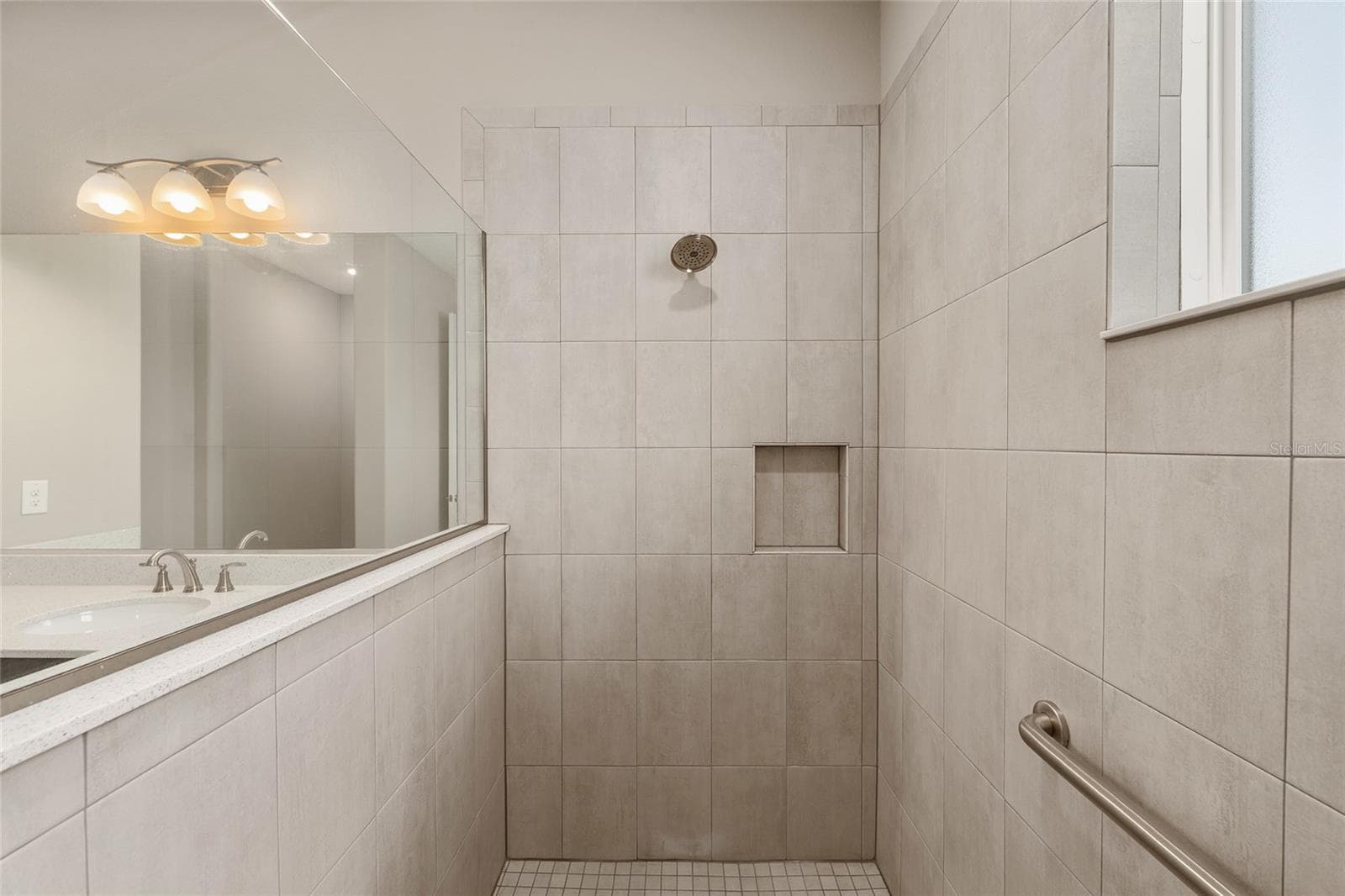 Closer view of the second primary ensuite shower, highlighting the built-in toiletry niche, conveniently positioned grab bar, and coordinating tile finishes for added functionality and comfort. - 8290 SW 92ND CIR, OCALA