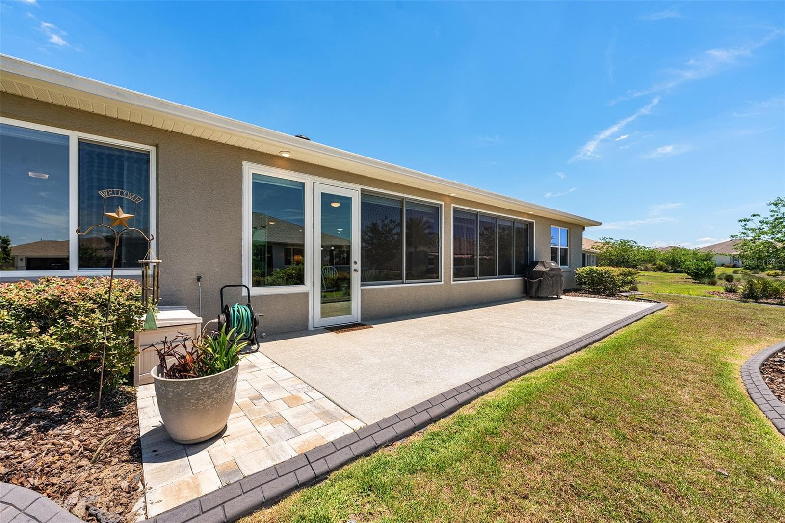 Expansive 38' x 10' patio featuring soffit lighting and a dedicated gas line for the included barbecue grill. Overlooking the beautifully landscaped backyard, this spacious outdoor retreat is ideal for grilling, entertaining, or simply enjoying Florida's beautiful weather. - 8290 SW 92ND CIR, OCALA