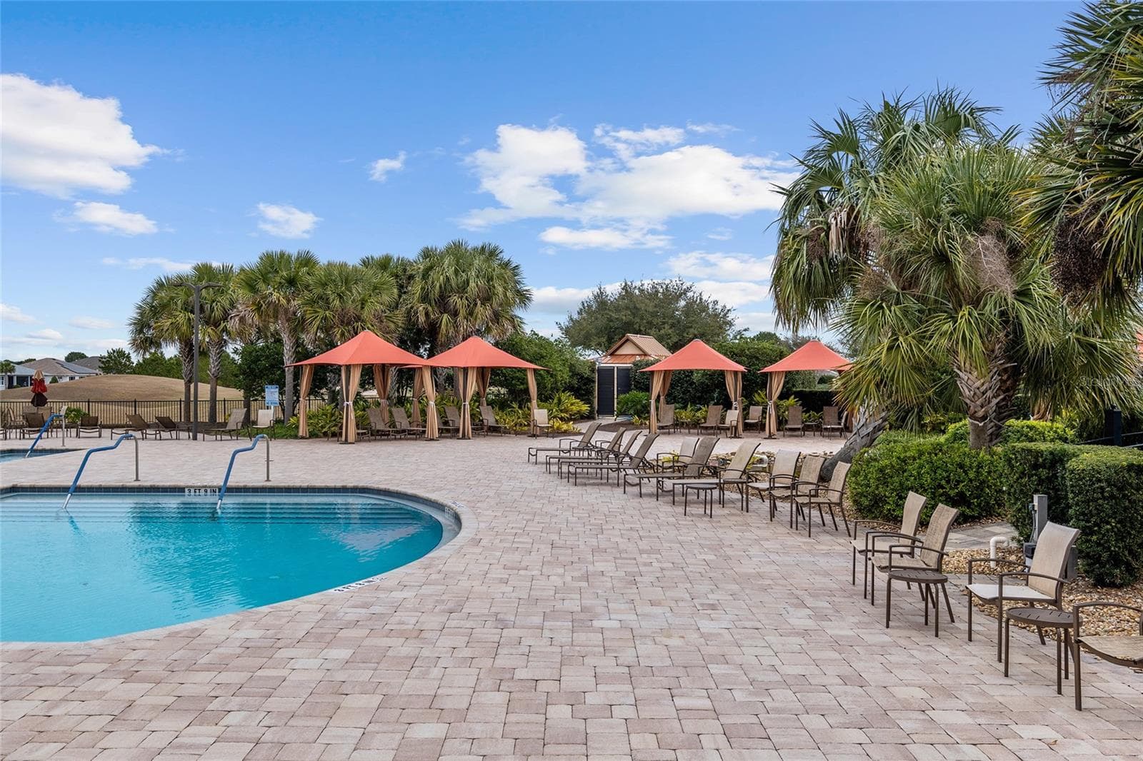 Relax poolside at Candler Hills, where inviting shaded cabanas, comfortable lounge seating, and lush tropical landscaping create a resort-inspired setting for unwinding, socializing, and enjoying the Florida sunshine. - 8290 SW 92ND CIR, OCALA
