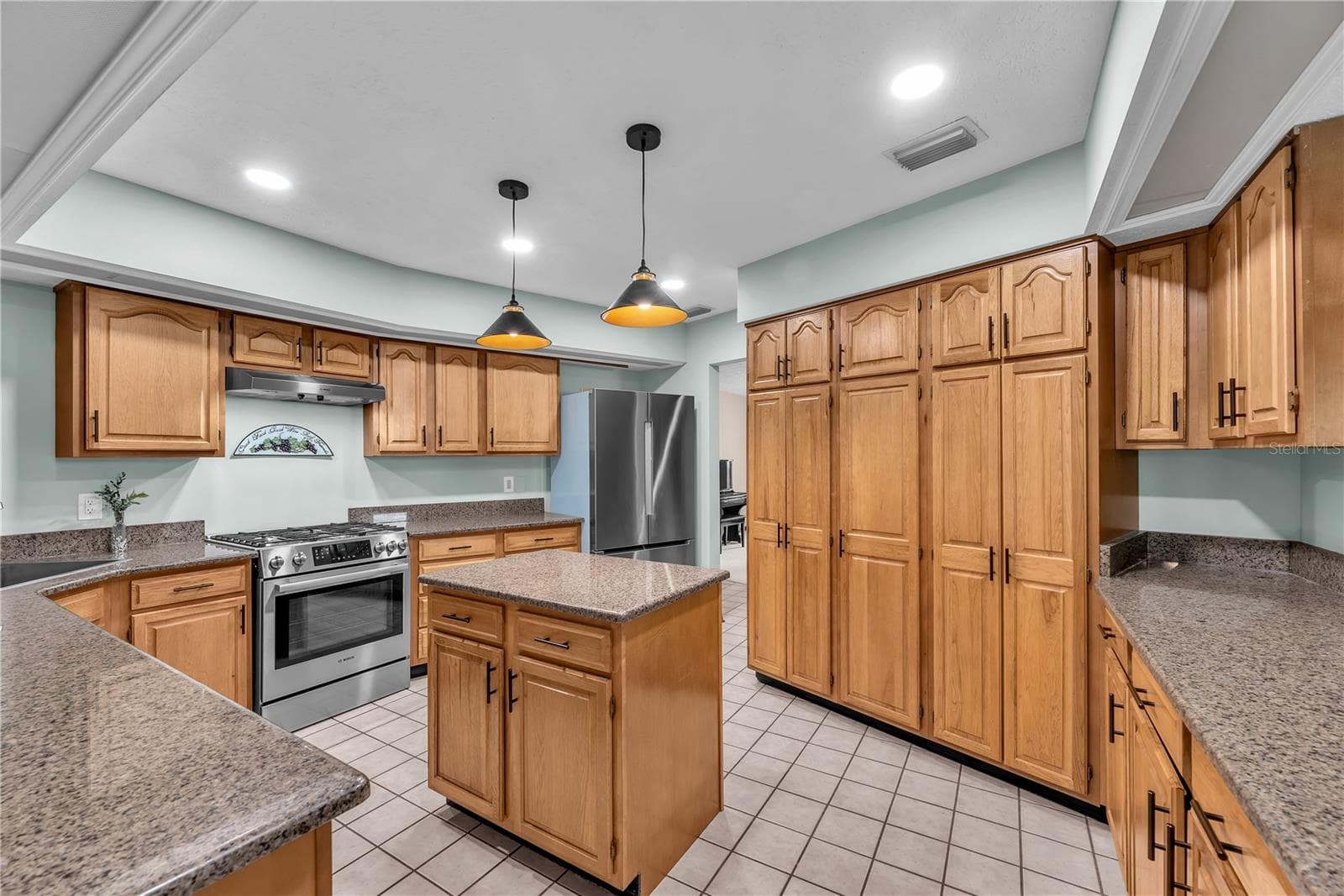 The beautifully appointed kitchen features rich wood cabinetry, gorgeous dark granite countertops, a large cabinet pantry for storage and updated lighting. - 2421 OAK LANDING DR, BRANDON
