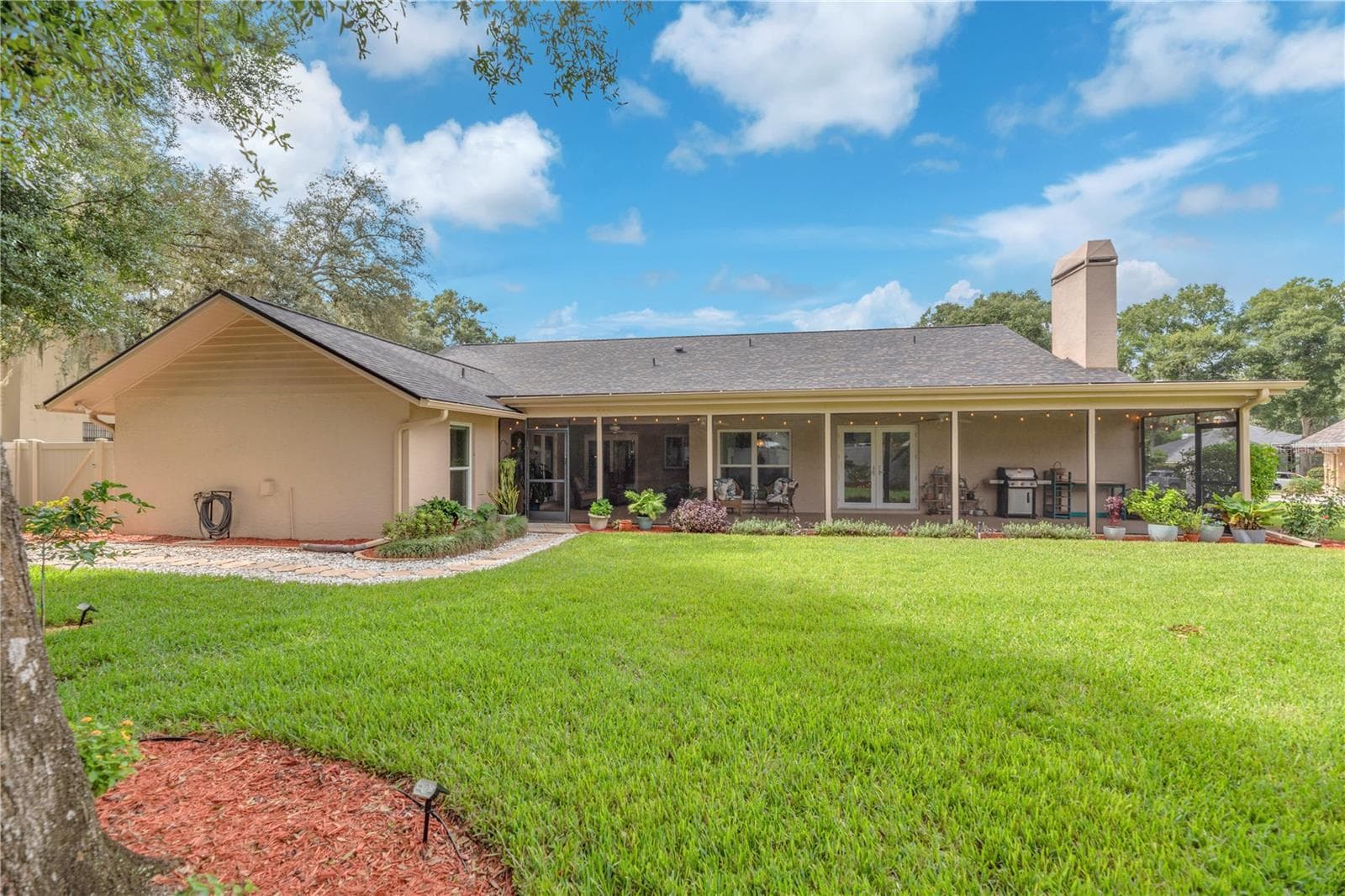 A view of the spacious screened lanai from the backyard fence facing west. - 2421 OAK LANDING DR, BRANDON