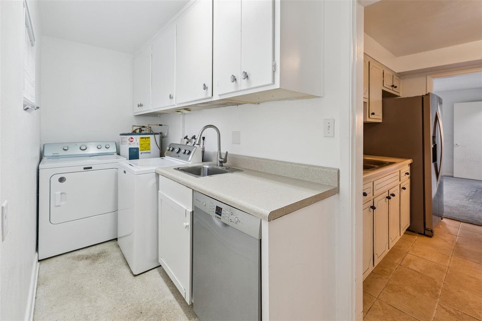 The walk-in pantry and laundry room provides abundant storage and includes a Bosch dishwasher, utility sink, washer and dryer, and access to the backyard - 803 HILLSIDE AVE, LAKE WALES
