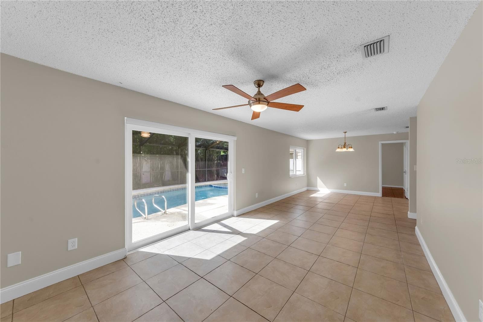 Tiled living room with back patio access through sliding doors - 9602 HIDDEN OAKS CIR, TAMPA