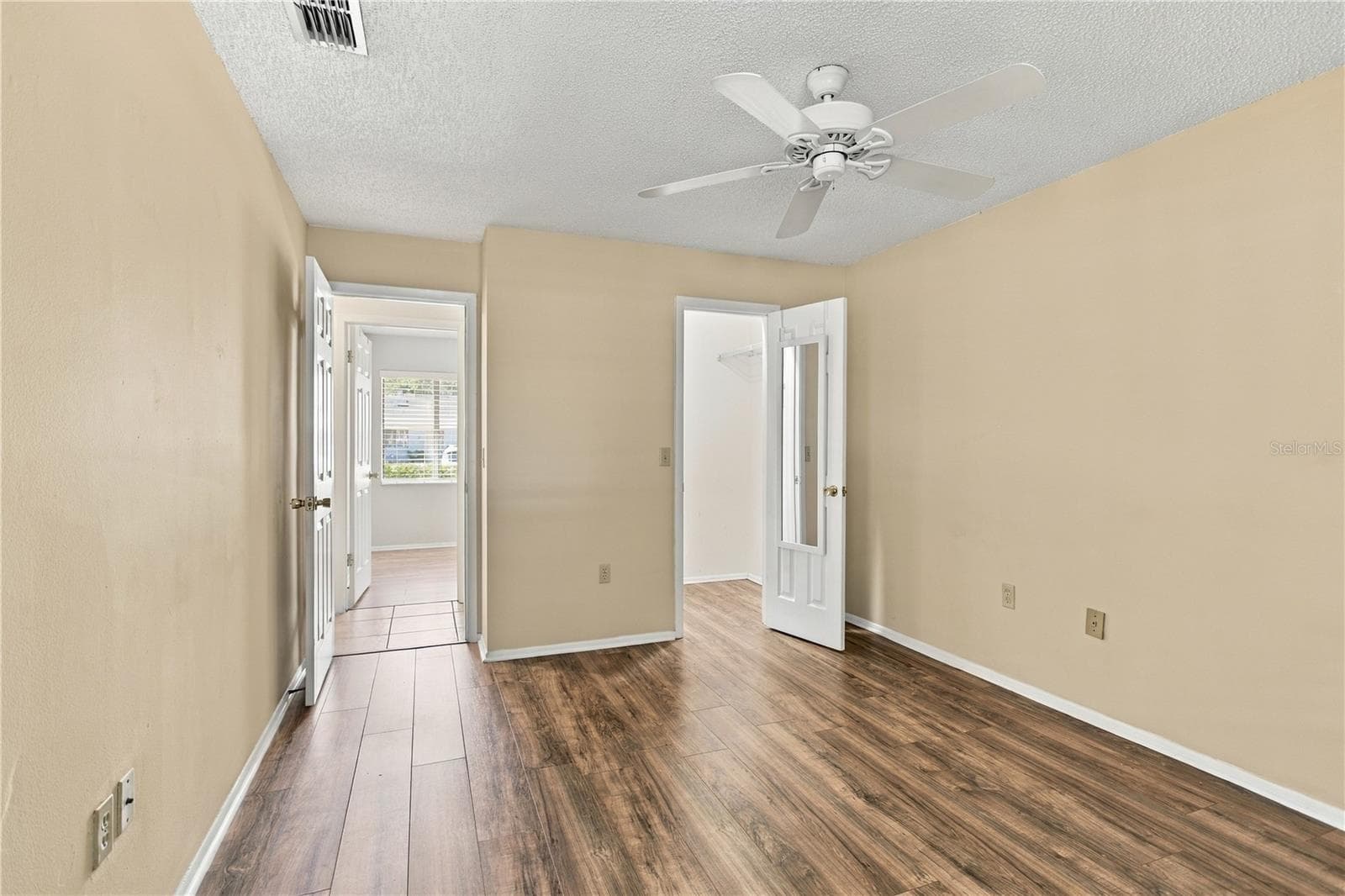 Primary Bedroom with walk-in closet, laminate floors and freshly painted neutral walls. - 9911 LANCEWOOD ST, ORLANDO