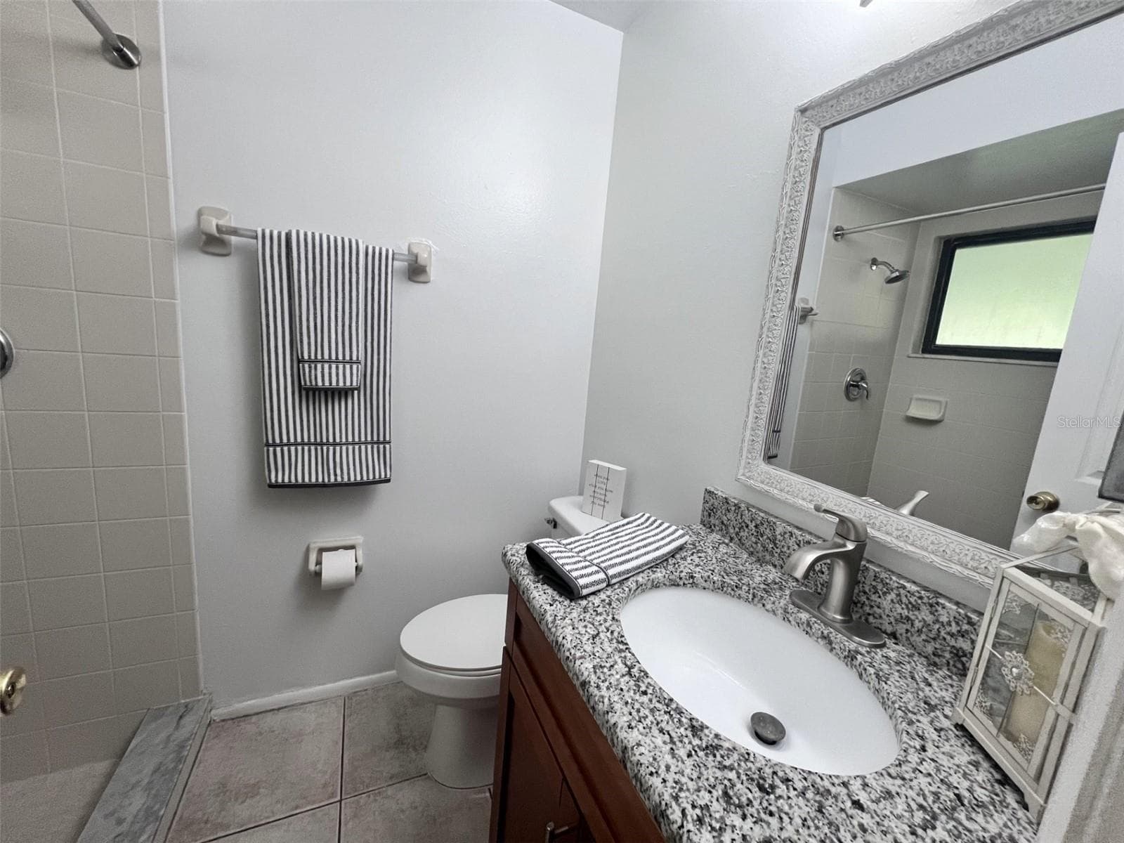 Primary bathroom with updated vanity, granite countertop and walk-in shower - 9911 LANCEWOOD ST, ORLANDO