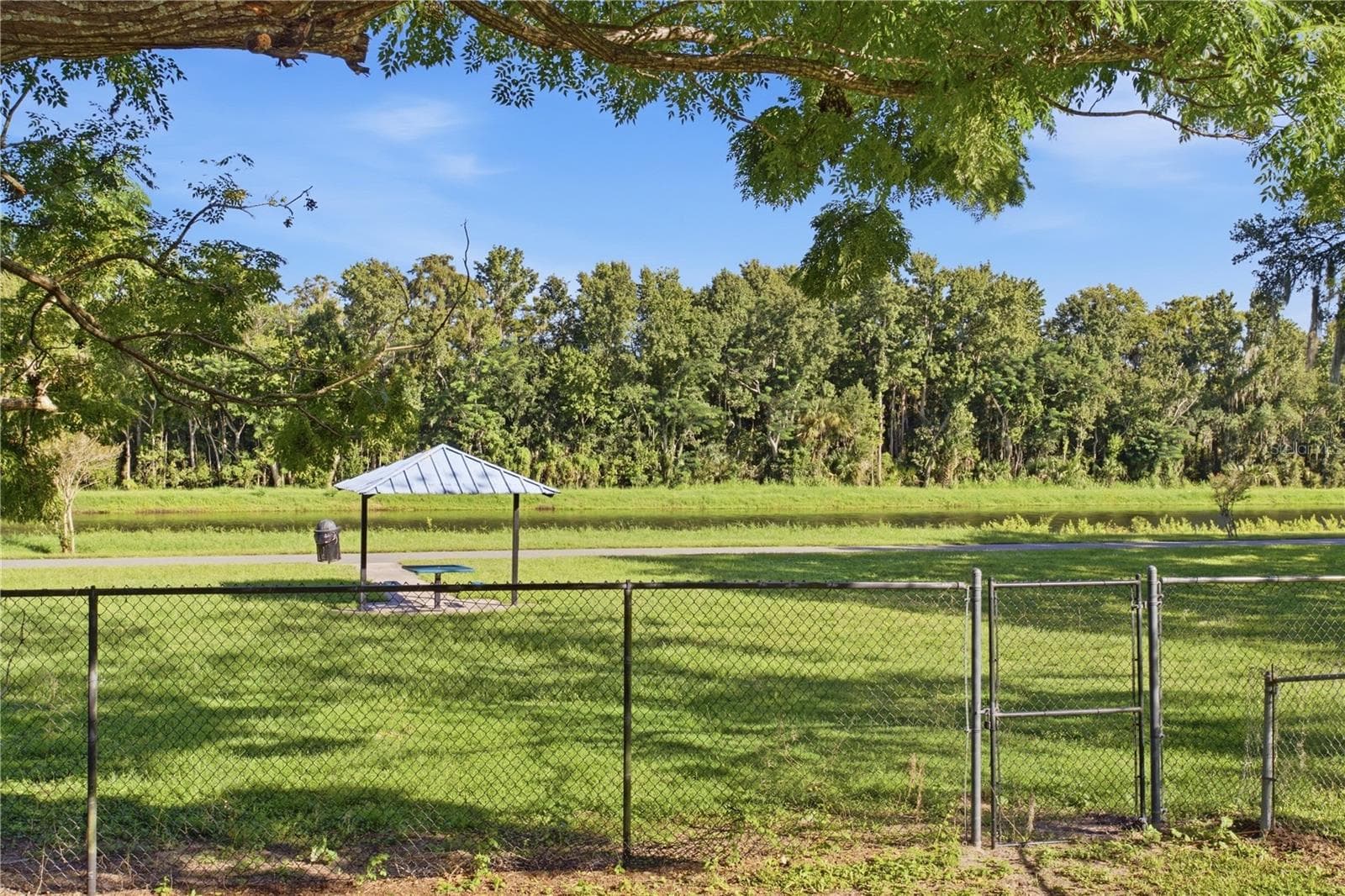 Fenced backyard with gate leading to trail, picnic table and river - 9911 LANCEWOOD ST, ORLANDO