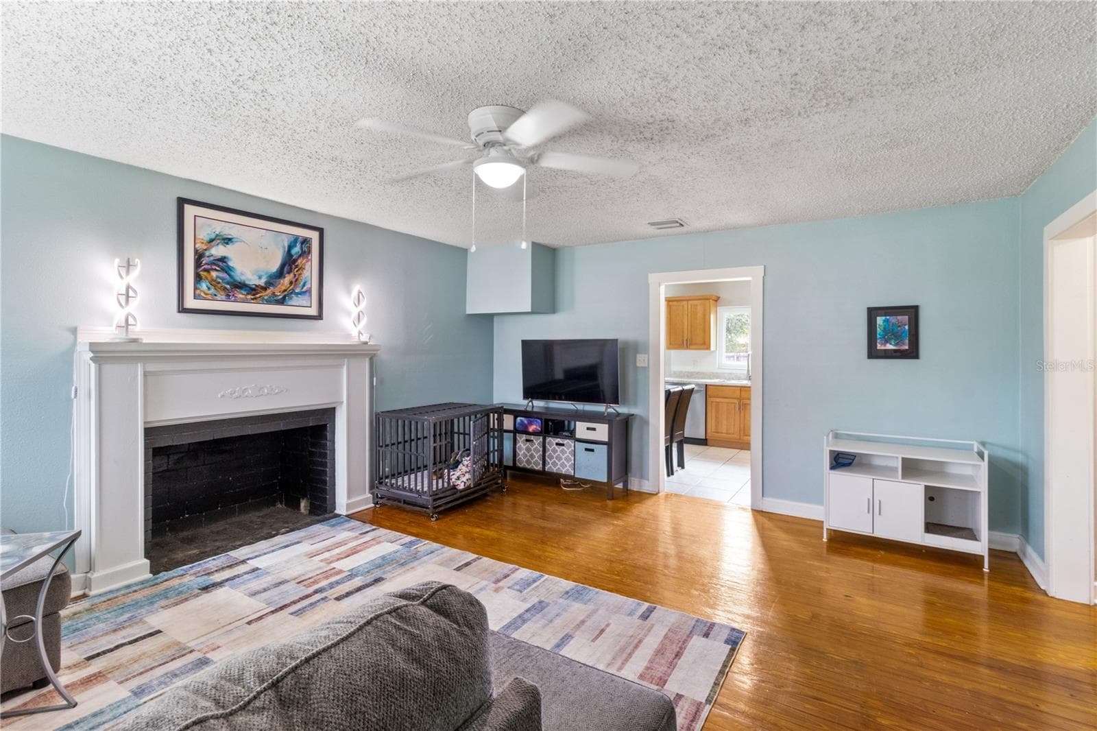 Living room with original hardwoods and decorative fireplace - 707 E CRAWFORD ST, LAKELAND