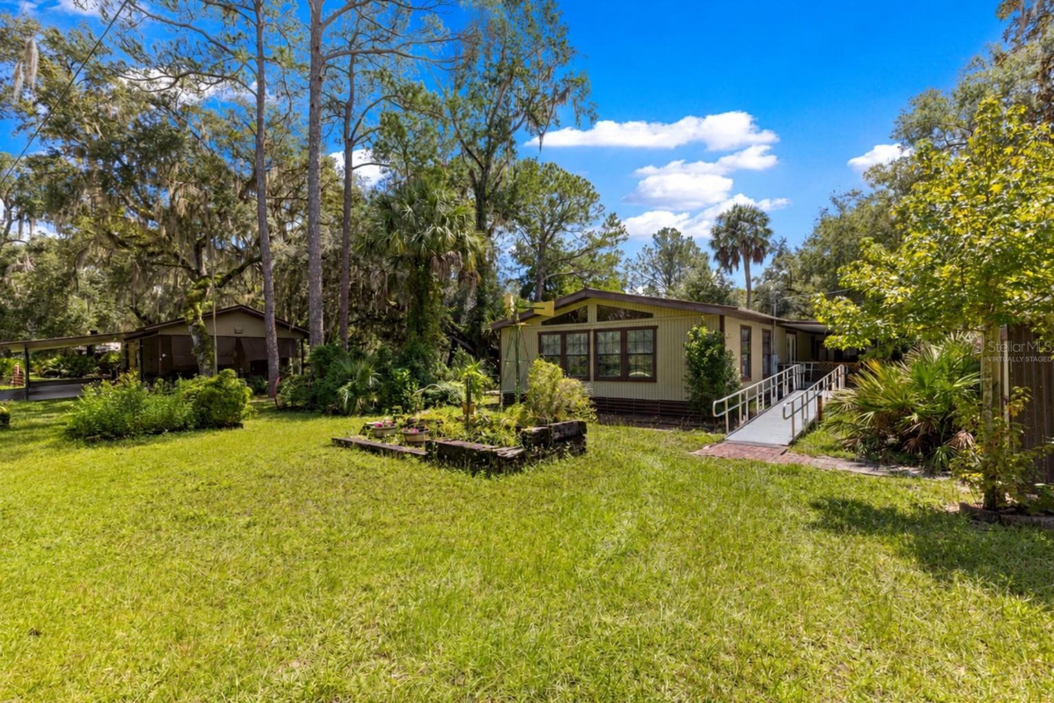 #1 · Main residence and ramp approach, with mature trees and lawn. Virtually staged—personal items digitally removed. - 7434 E CABIN LN, INVERNESS