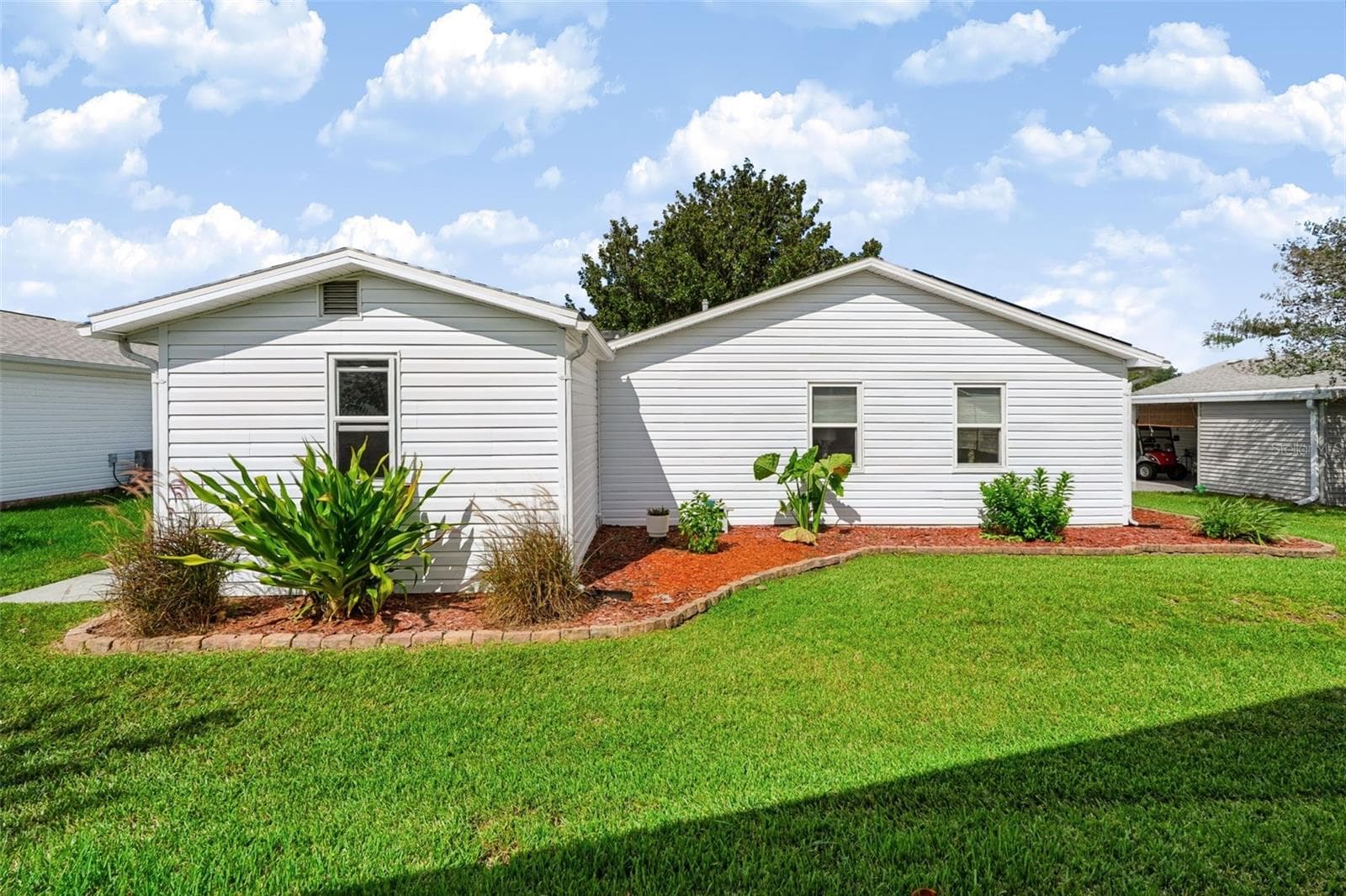 Backside of home with landscaping - 1220 MARIA CT, LADY LAKE