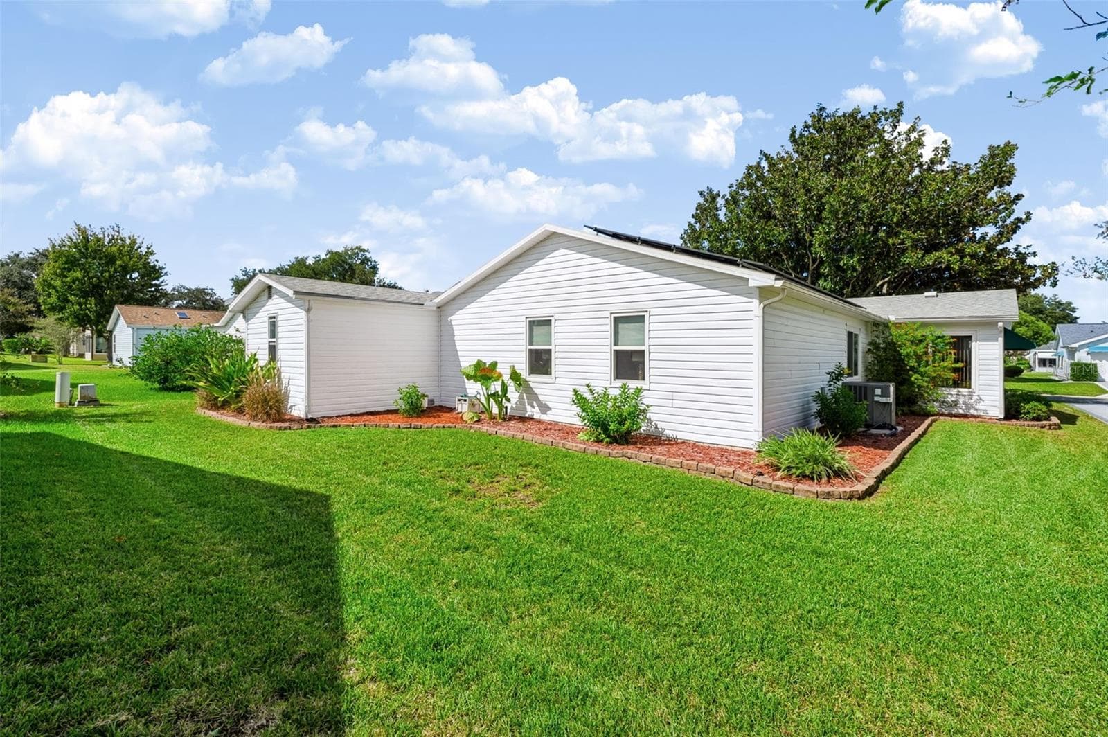 Backside of home with landscaping - 1220 MARIA CT, LADY LAKE