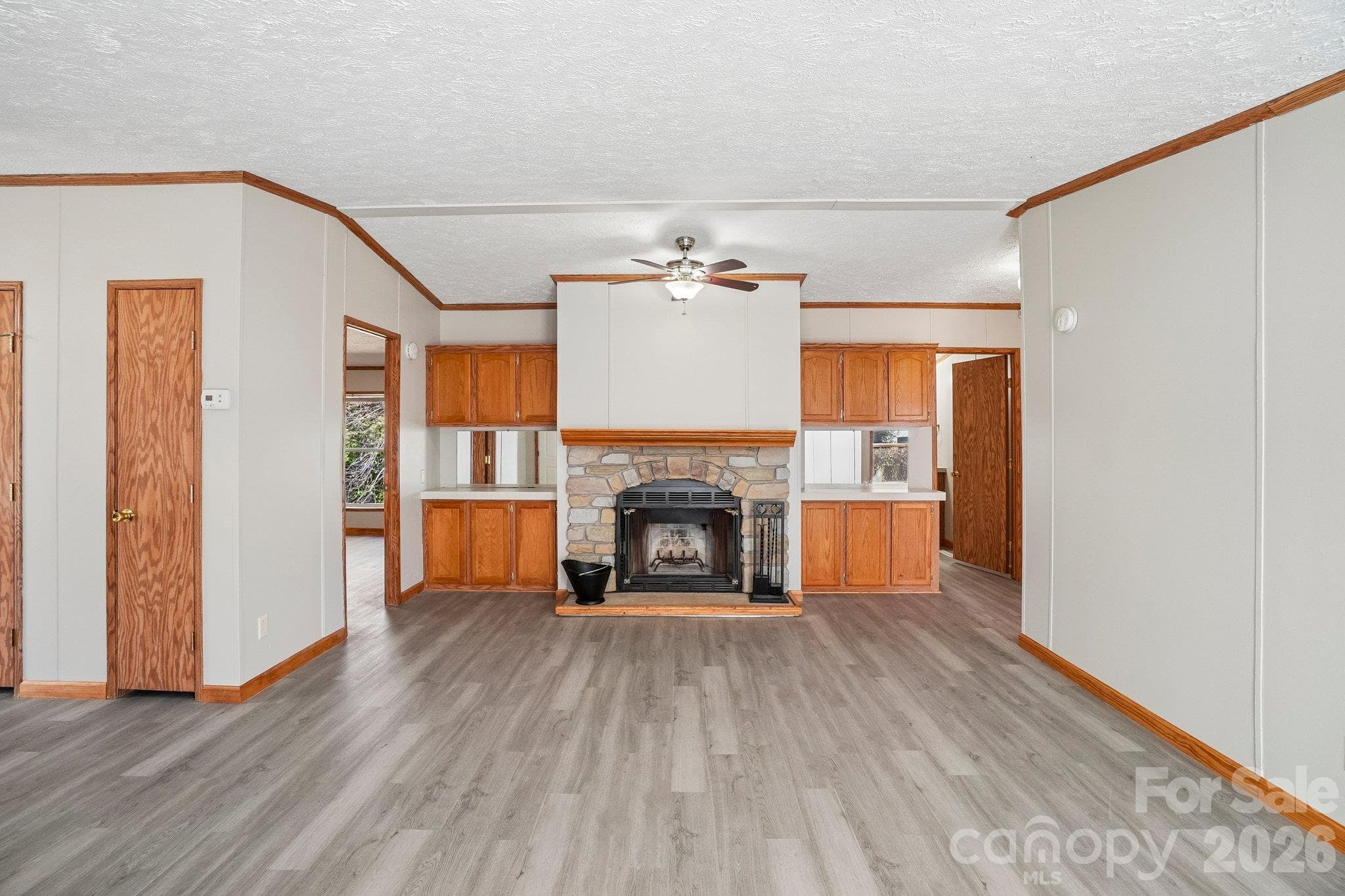 Enter into a family room featuring a wood burning fireplace bracketed by storage cabinetry. - 202 Banyan Road, Candler