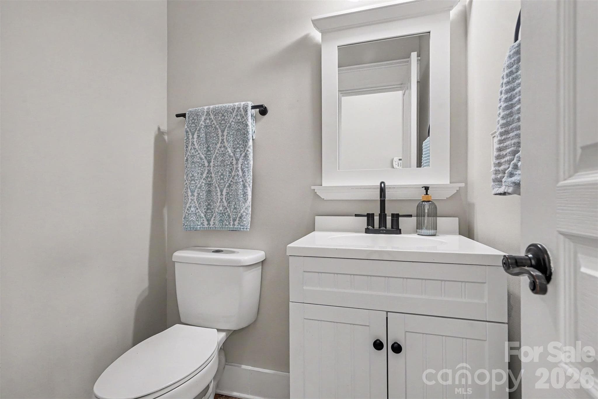 Half Bathroom located on the main level. Fresh, neutral paint. White cabinet and mirror add a sleek look to this beautiful space. - 3585 Leighton Drive SW, Concord