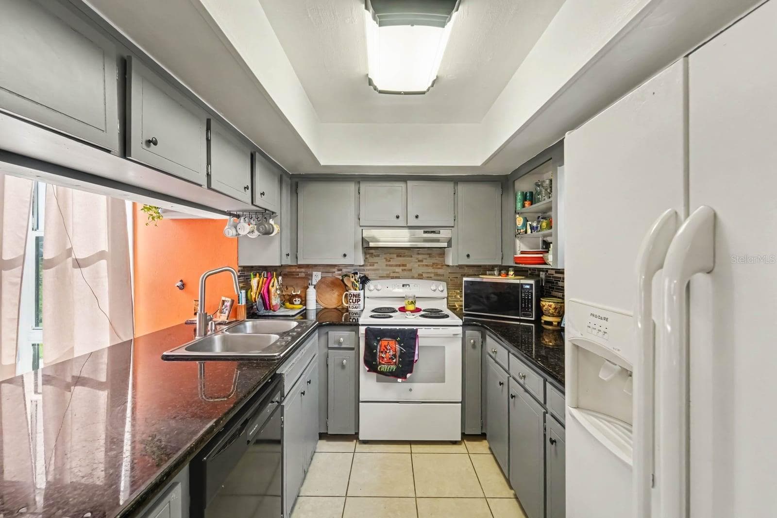 Galley kitchen features gray cabinetry, dark countertops & brick backsplash - 1055 ENCOURTE GREEN, APOPKA