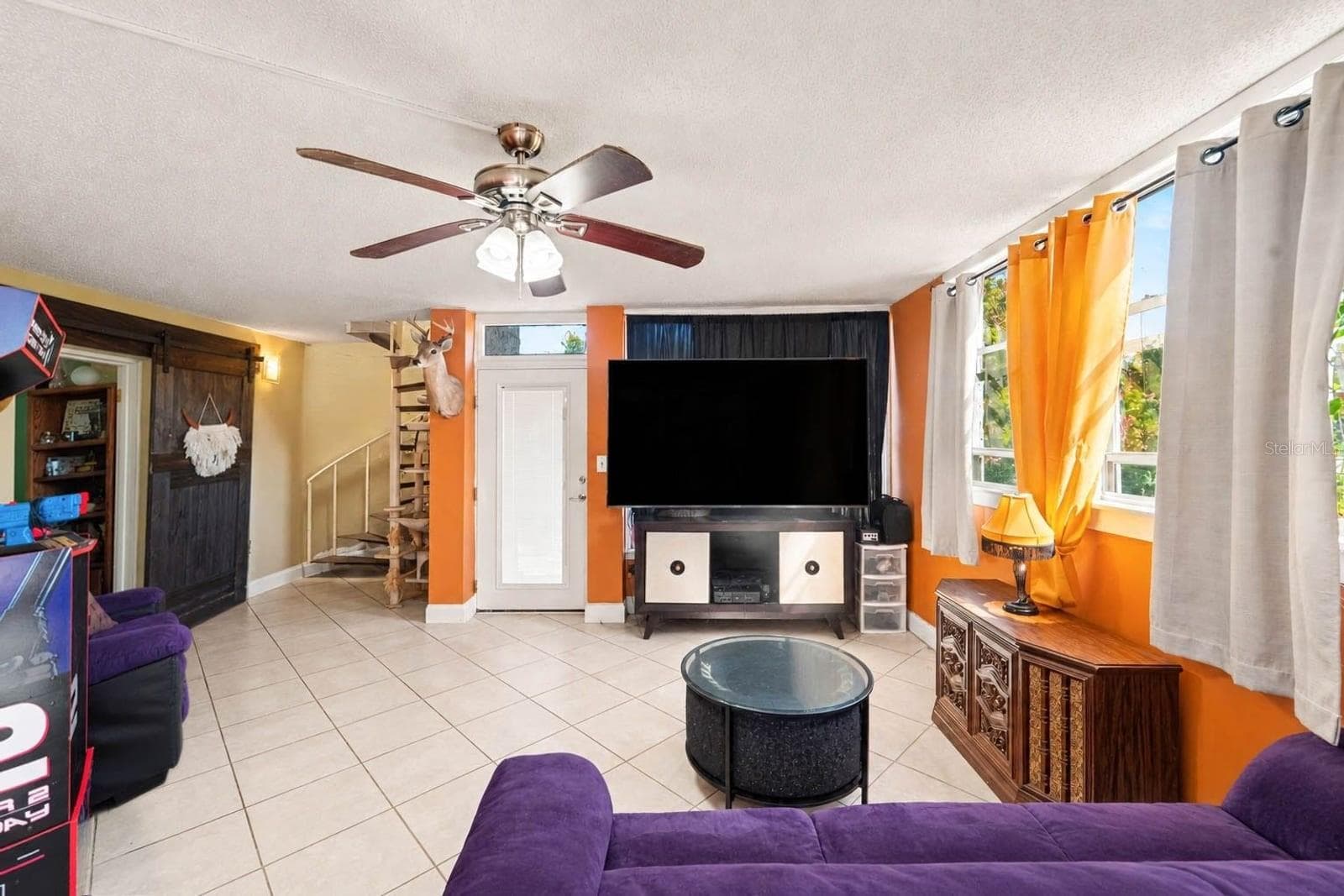 Spacious Living Room with Orange Accent Walls & Entertainment Setup - 1055 ENCOURTE GREEN, APOPKA
