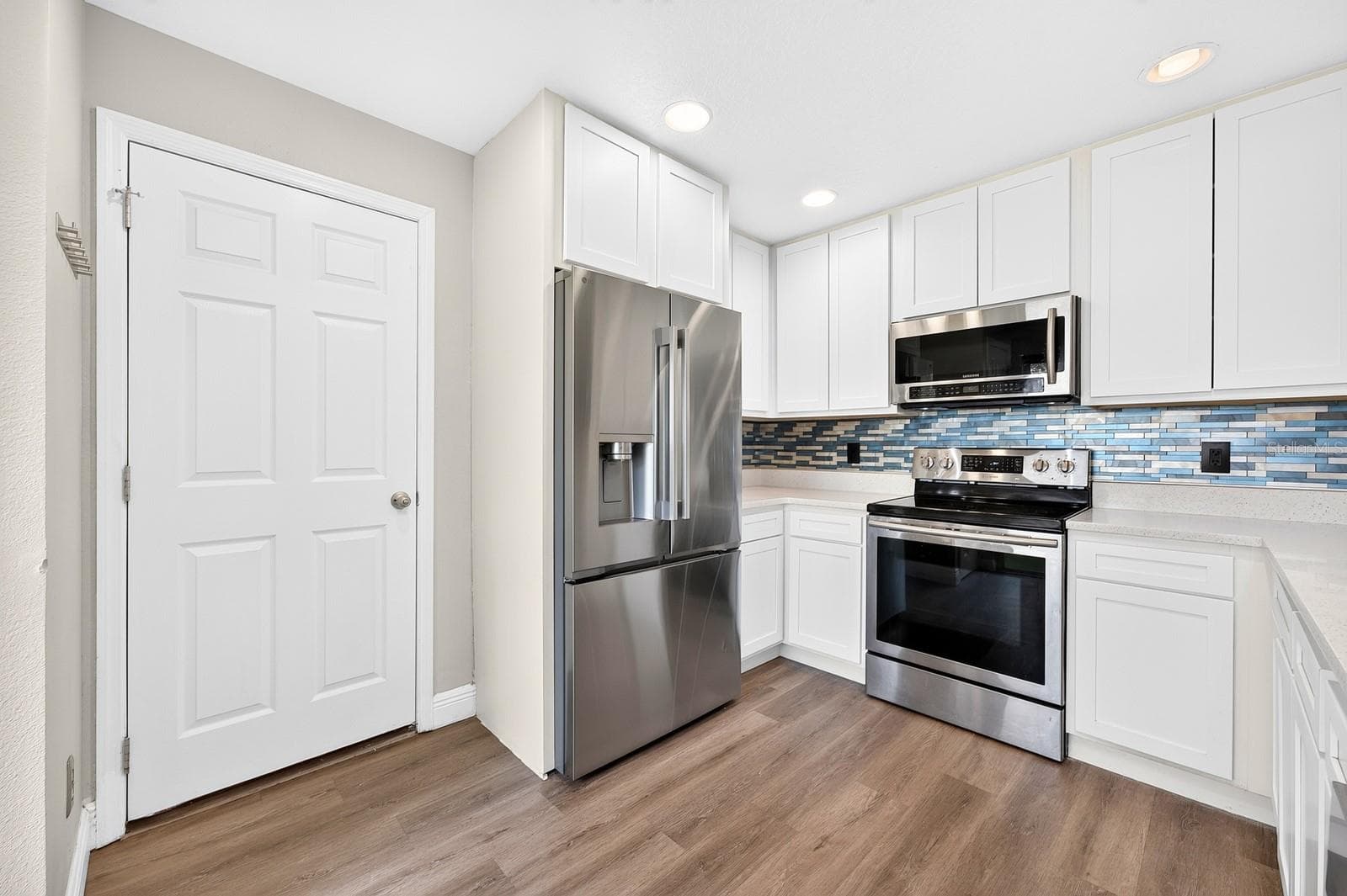 RECESSED LIGHTING brightens the space, while the NEW STAINLESS STEEL REFRIGERATOR (2025) and NEW BACKSPLASH (2025) complete the polished look. - 13028 AUBURN COVE LN, ORLANDO