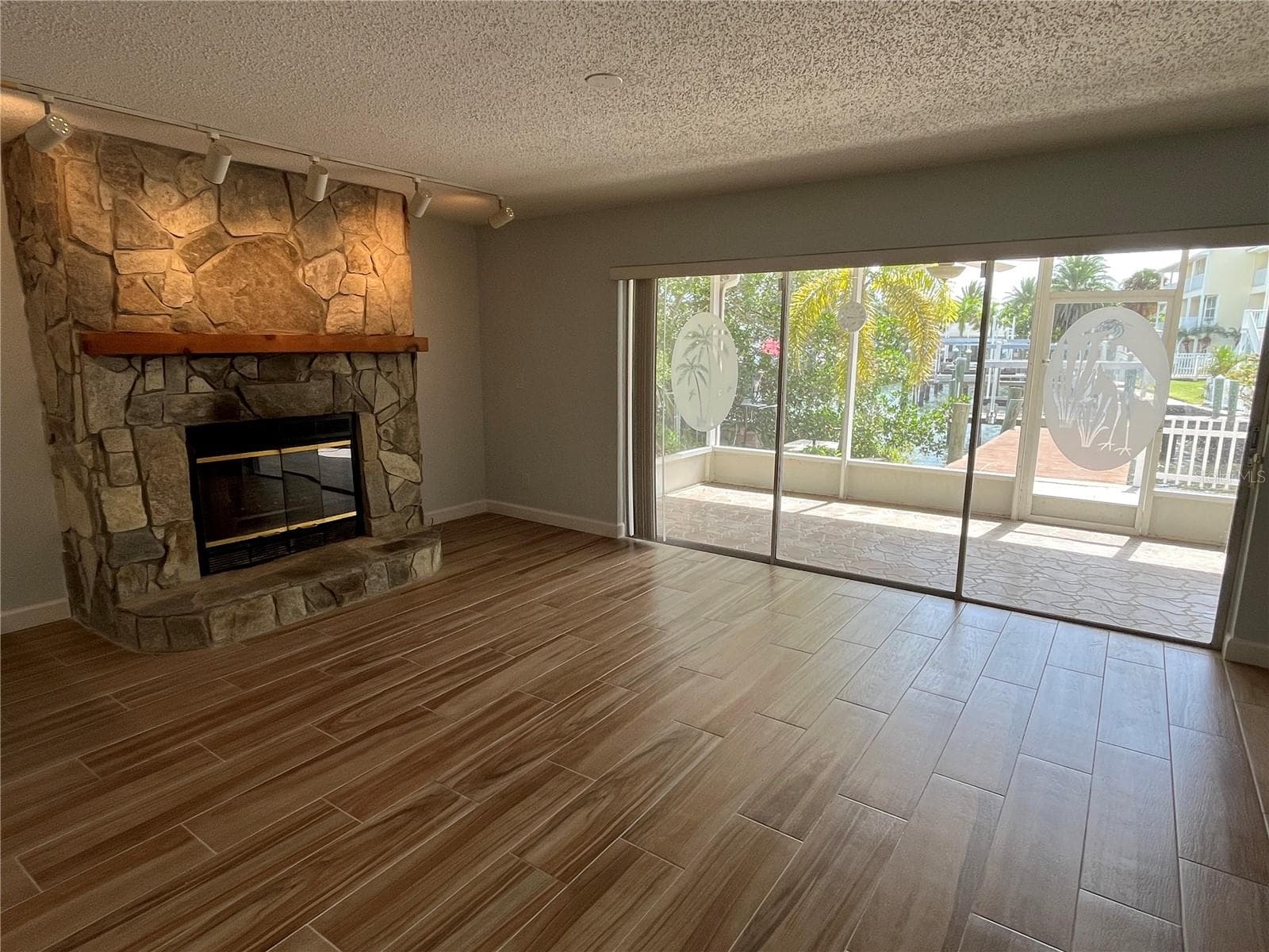 Living room with covered patio access and view of the canal - 307 LA HACIENDA DR, INDIAN ROCKS BEACH