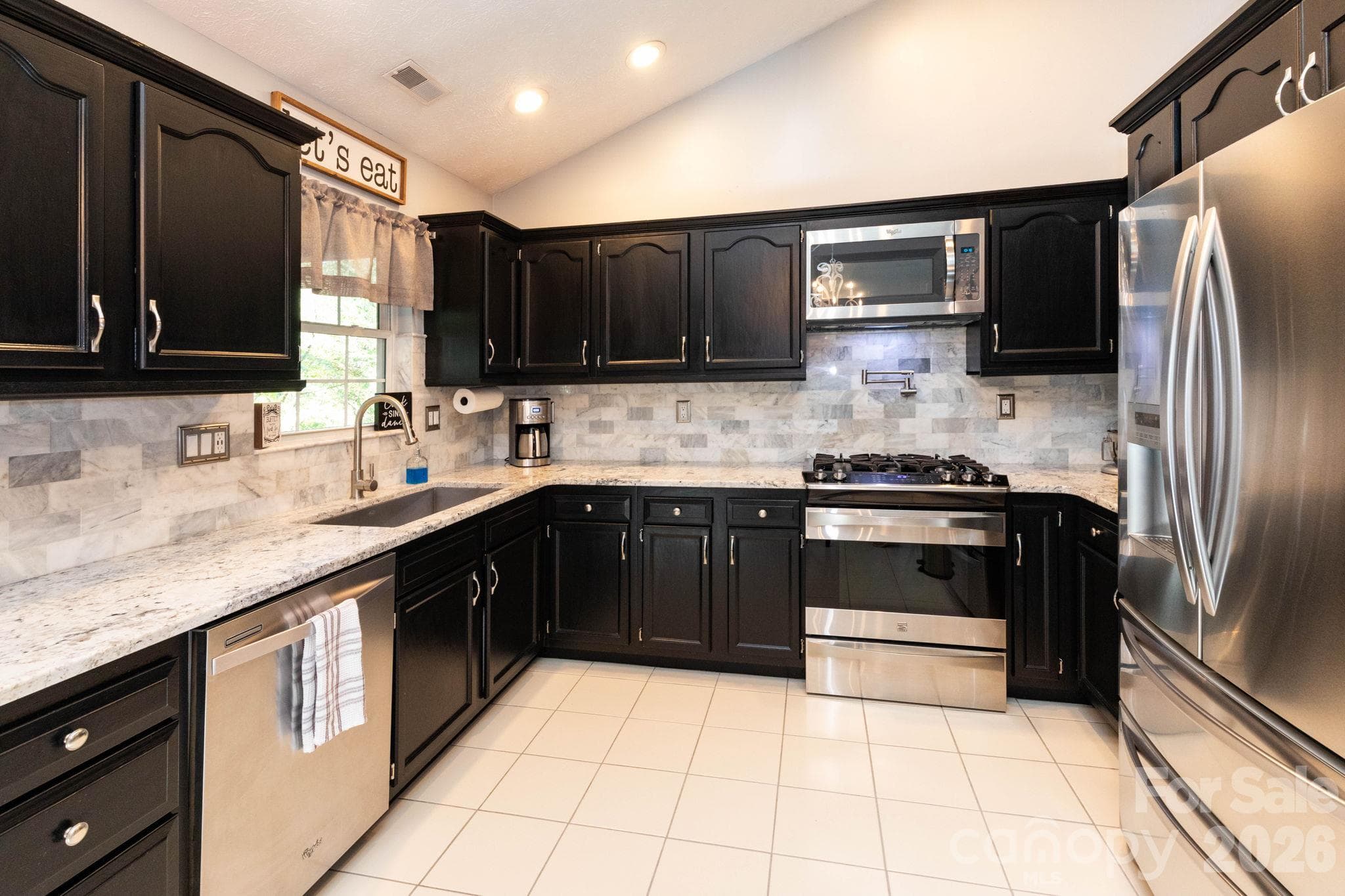 Well-appointed kitchen featuring dark cabinetry, stainless steel appliances, light countertops, tile backsplash, and recessed lighting. - 139 Lone Eagle Lane, Hendersonville