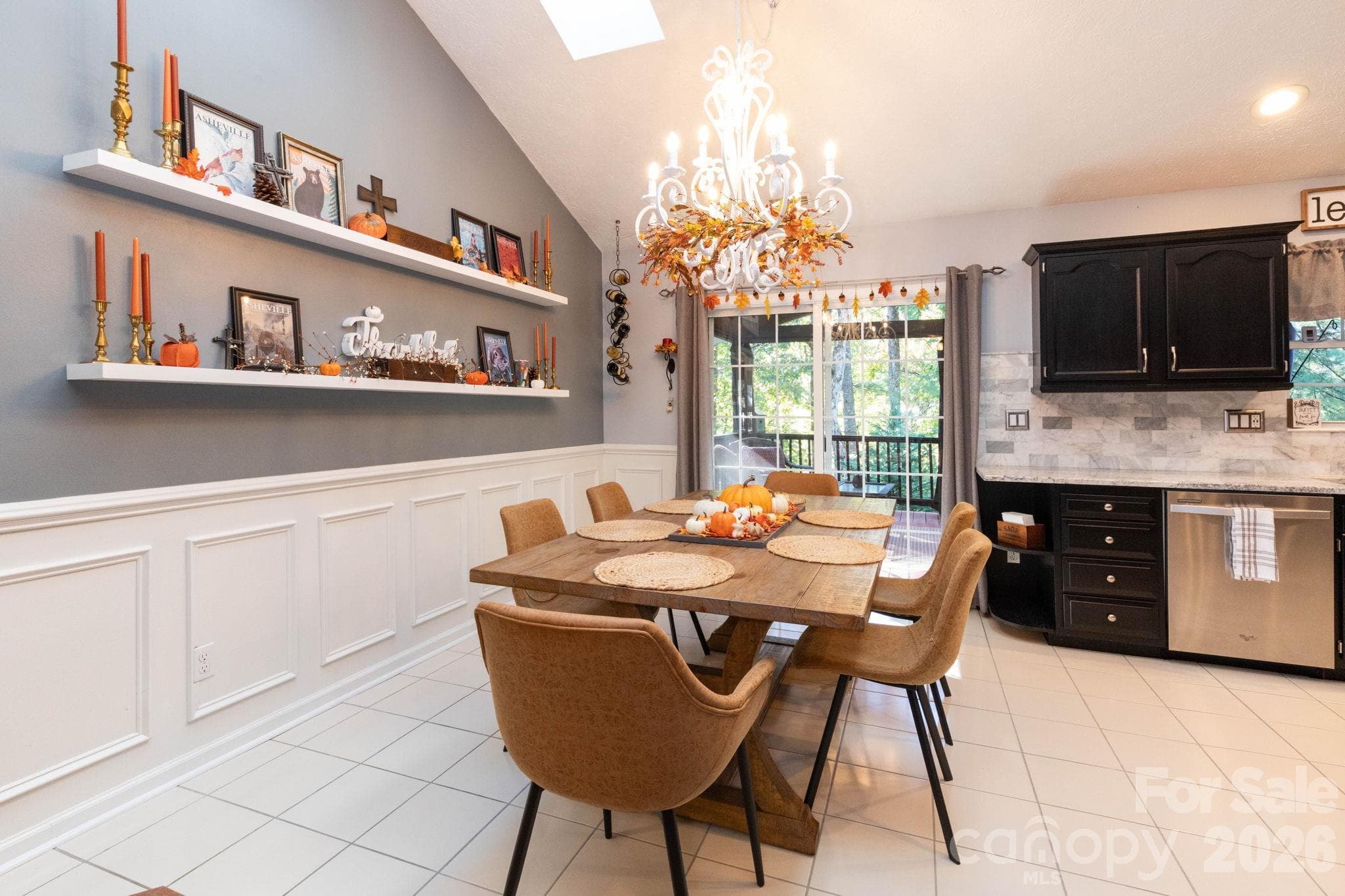 Dining area featuring a chandelier, decorative wall paneling, open display shelving, and convenient access to the kitchen and outdoor deck. - 139 Lone Eagle Lane, Hendersonville